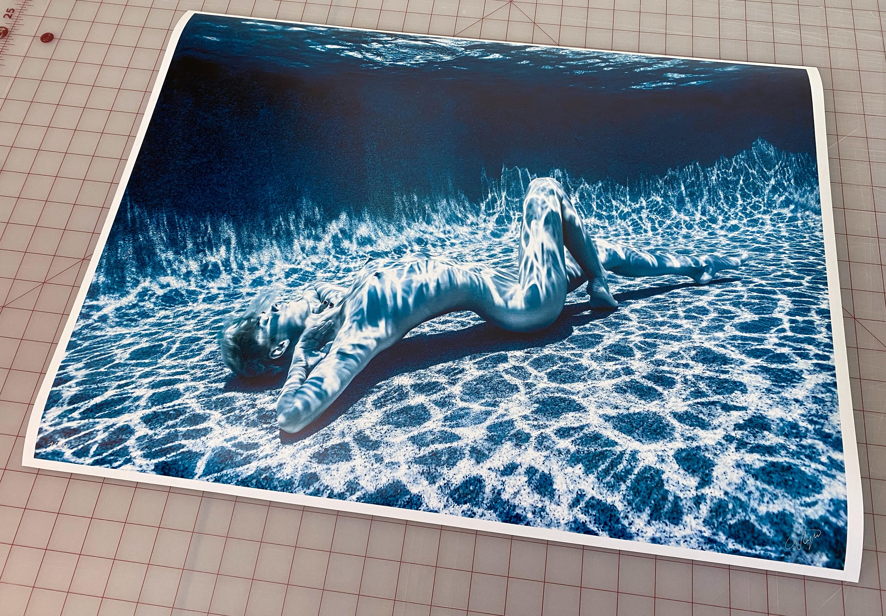 A beautiful  and sophisticated underwater photograph of a young naked woman on her back on the bottom of the pool.  This is a monochrome photograph  close to black and white with reach aquatic tint.
This is the first photo from the Moonlight