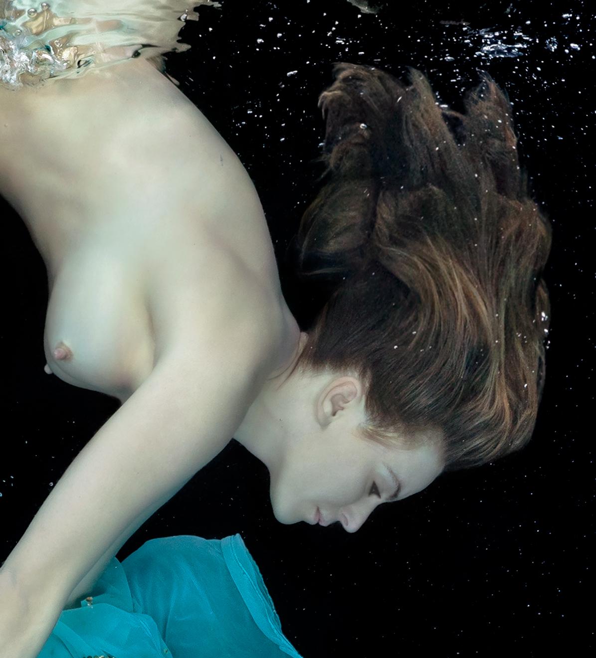 An underwater photograph of a naked young women diving next to the bright turquoise dress she just took off. 

Original gallery quality print signed by the artist. 
Digital archival pigment print. 
Paper size 36