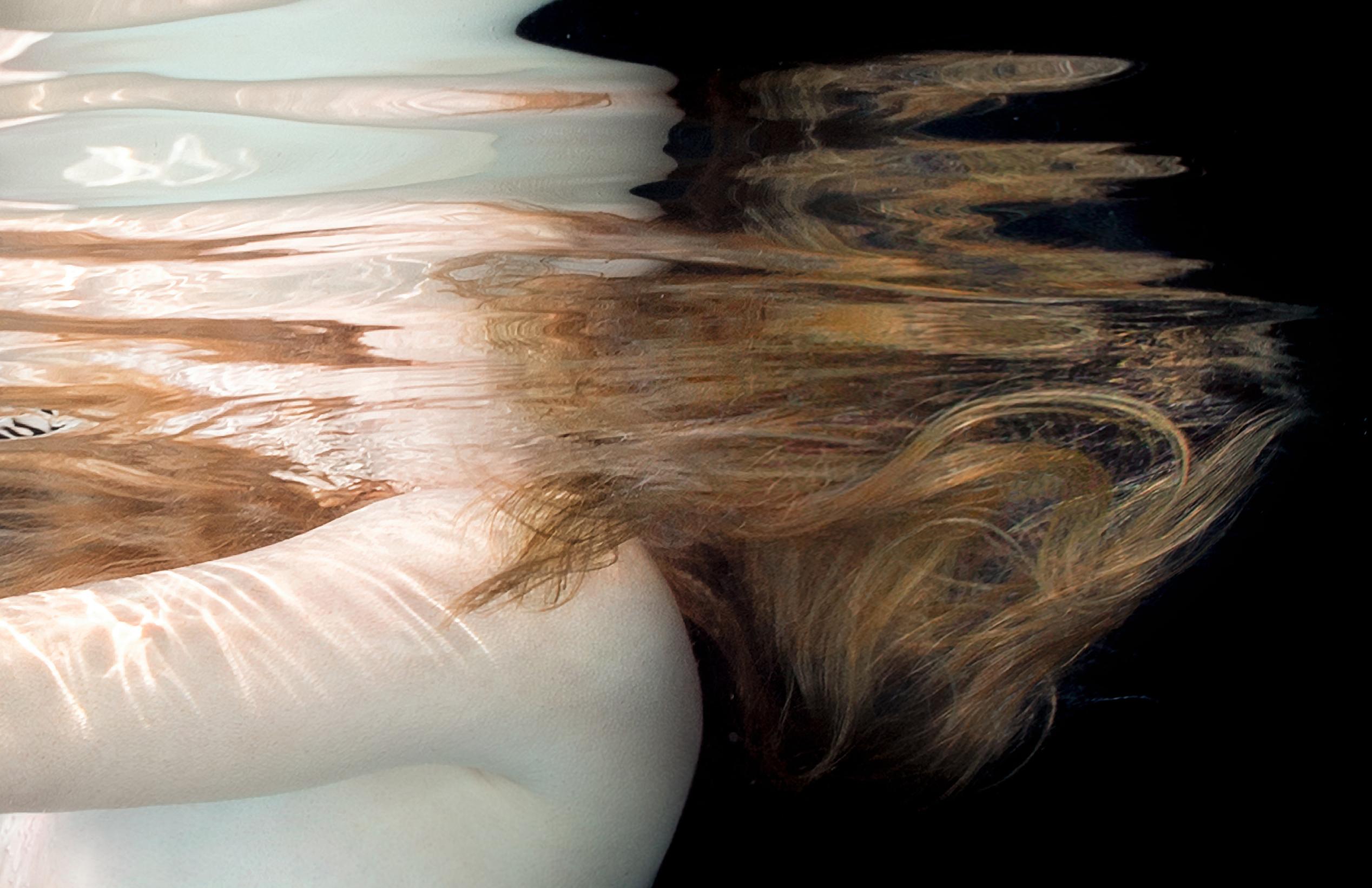 Underwater photograph of two naked girls holding their hands. Their heads remain above the water and are not visible. This photograph belongs to the series Porcelain. The series includes my favorite photographs of nude models in the porcelain color