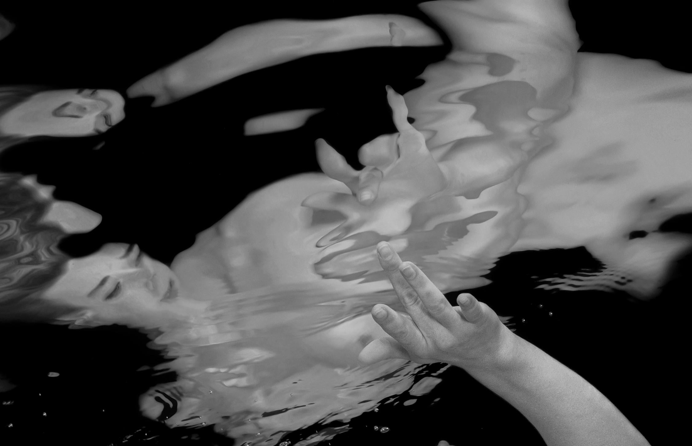 Unterwasser-Schwarz-Weiß-Fotografie einer jungen nackten Frau, die ihr Spiegelbild in der Wasseroberfläche berührt. 

Original-Pigmentdruck in Galeriequalität auf Archivpapier, vom Künstler signiert.
Limitierte Auflage von 24 Stück
Papierformat: