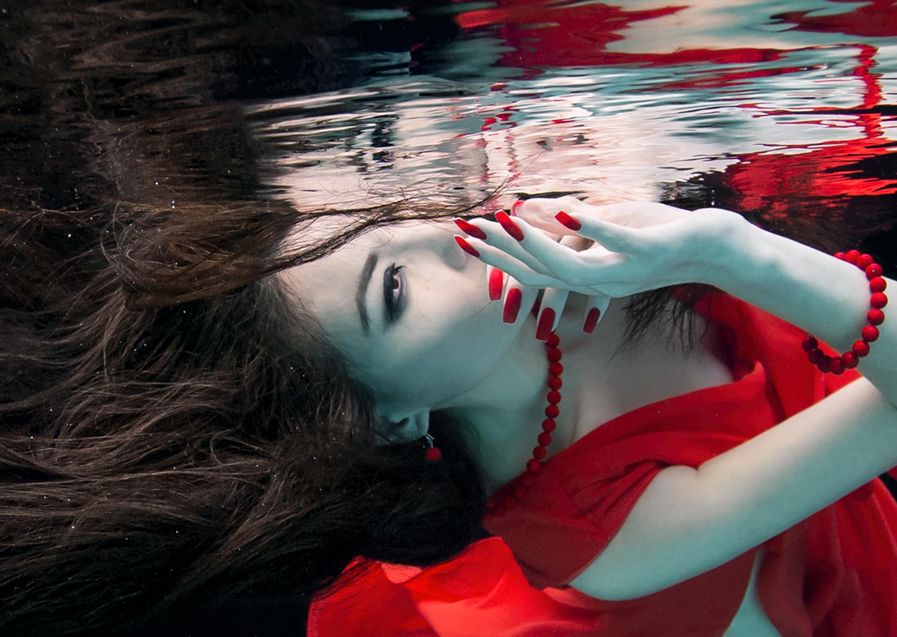 Unterwasserfoto eines hübschen Mädchens mit dunklen Haaren in rotem Kleid.

Originalabzug in Galeriequalität auf Archiv-Metallic-Papier, vom Künstler signiert.
Papierformat: 36