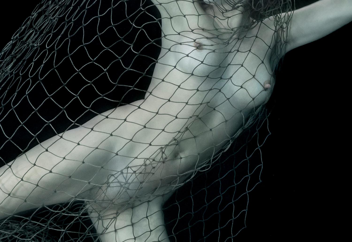 Ein Unterwasser-Aktfoto einer jungen Frau, die sich in einem Fischernetz verfangen hat.

Vom Künstler signierter Originaldruck in Galeriequalität. 
Digitaler Pigmentdruck auf Archivierungspapier mit Metallic-Finish. 
Papierformat: 25