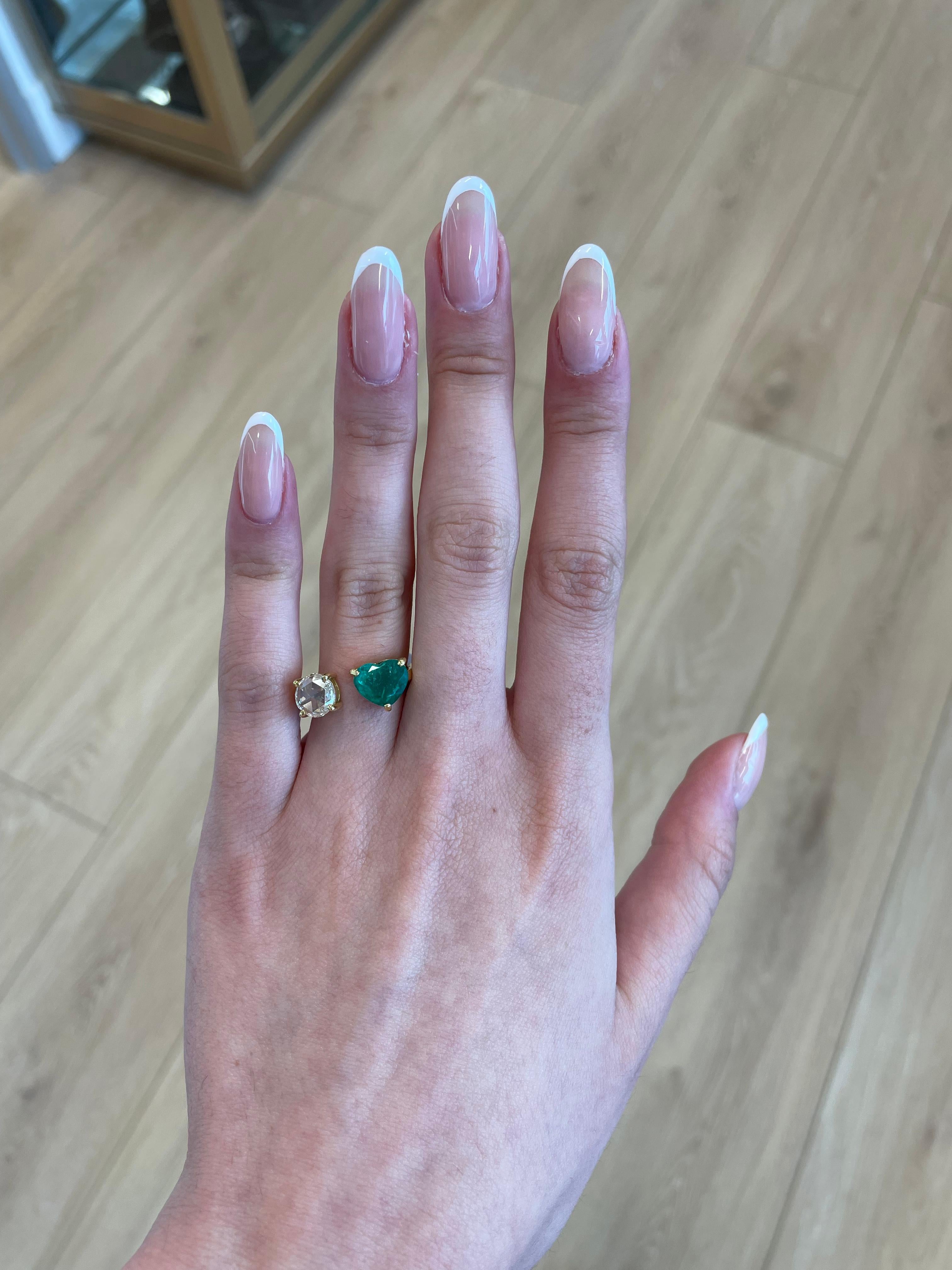 Stunning modern floating emerald and diamond toi et moi ring. By Alexander Beverly Hills.
1 heart shape emeralds, 2.10 carats apx F2. 1 round rose cut diamond 0.87 carats, approximately G/H color and vs clarity. 18-karat yellow gold, 5.27 grams,