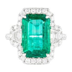 Alexander 6.26ctt Emerald with Diamond Three Stone Halo Ring 18 Karat Gold Alexander 6.26ctt Emerald with Diamond Three Stone Halo Ring 18 Karat Gold