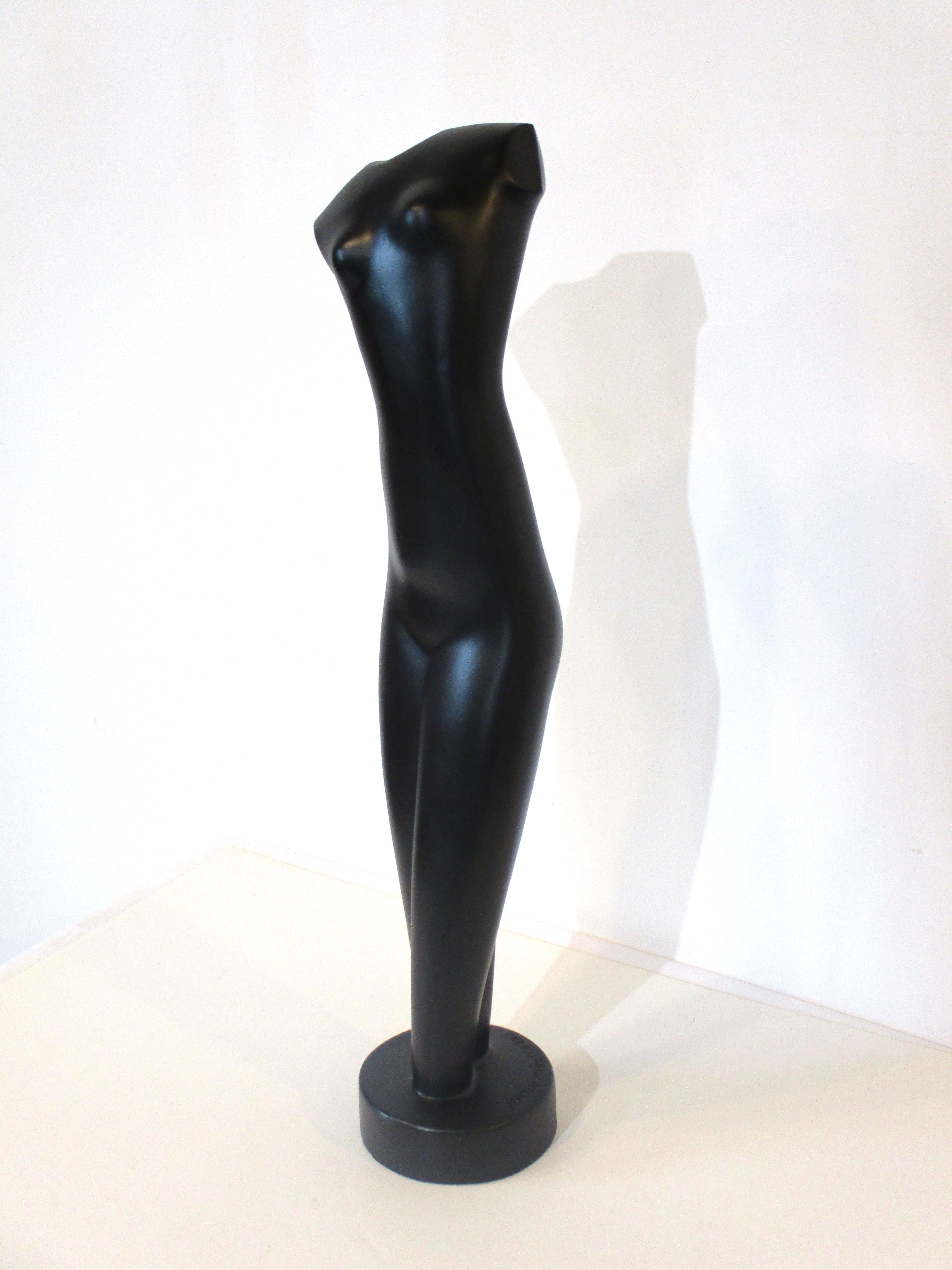 A cast nude sculpture of a women in a satin black finish with rounded base titled 