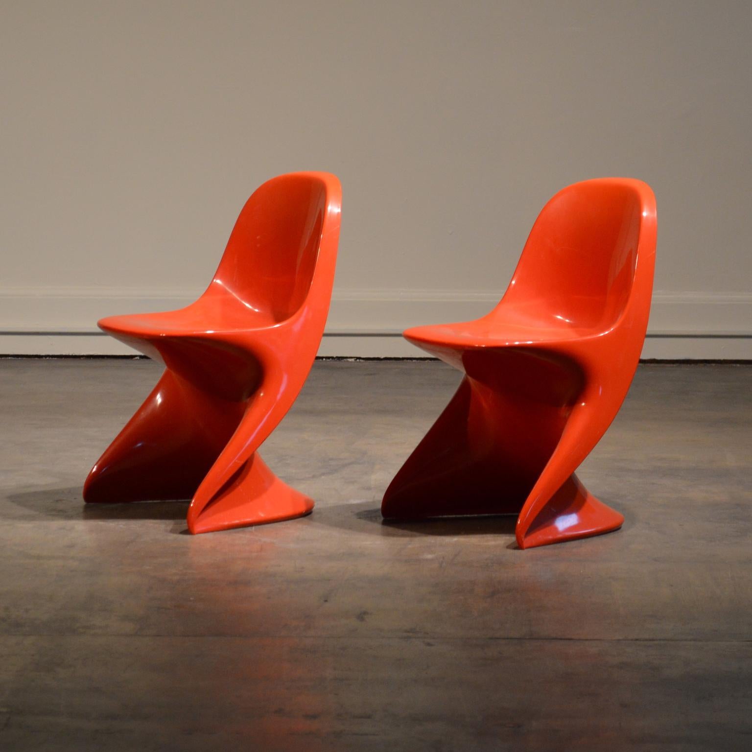 Pair of red Alexcander Begge children's chairs with a silhouette similar to Verner Panton's S-chair. These are child-sized stacking chairs molded from a single piece of ABS plastic. Light-weight and sturdy. Easy to clean. Perfect for a little one's