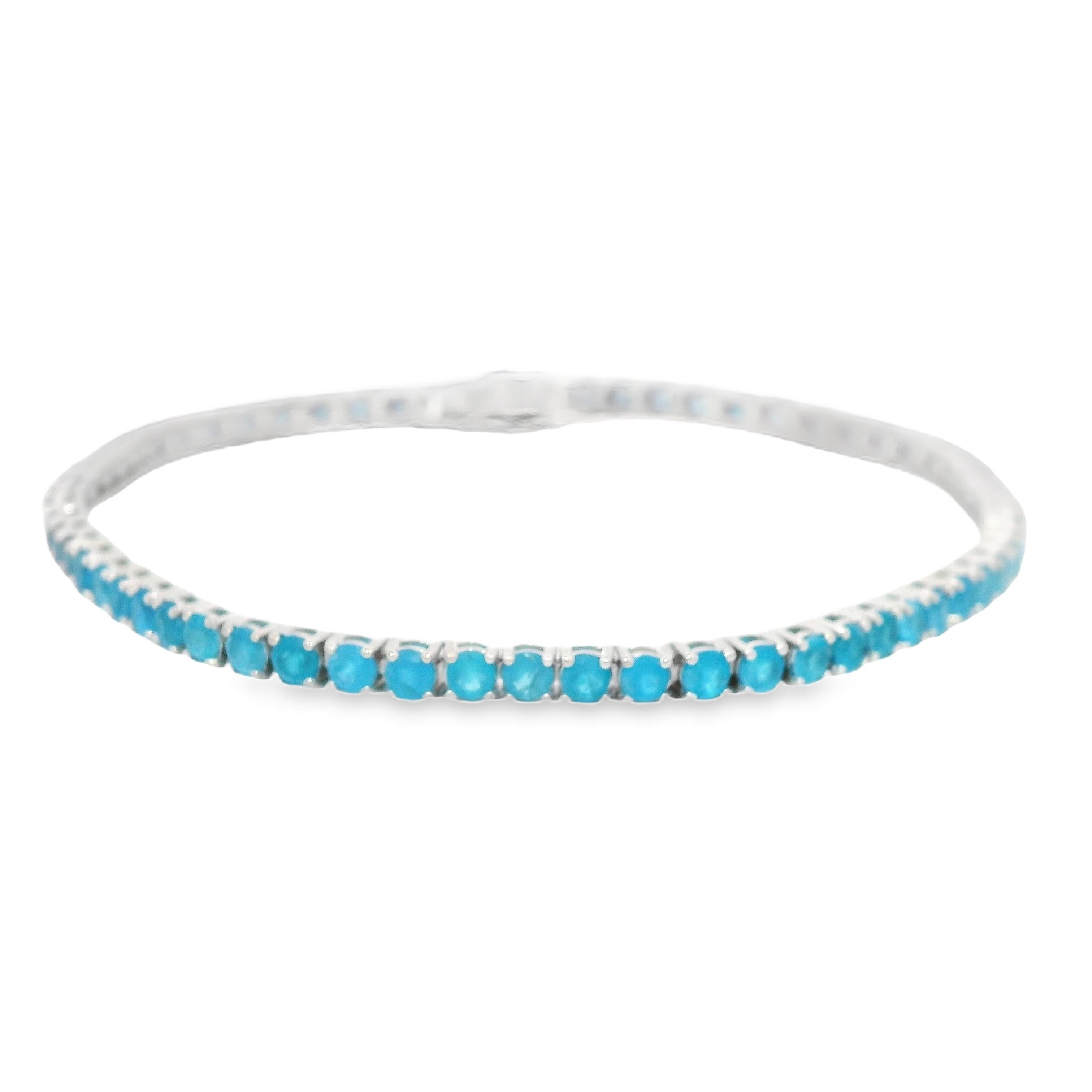 Exquisite and neon blue tennis bracelet, paraiba tourmaline like color, by Alexander Beverly Hills.
65 round blue apatite, 4.91 carats total. Four prong set in 18-karat white gold, 8.23 grams, 7 inches.
Accommodated with an up-to-date digital