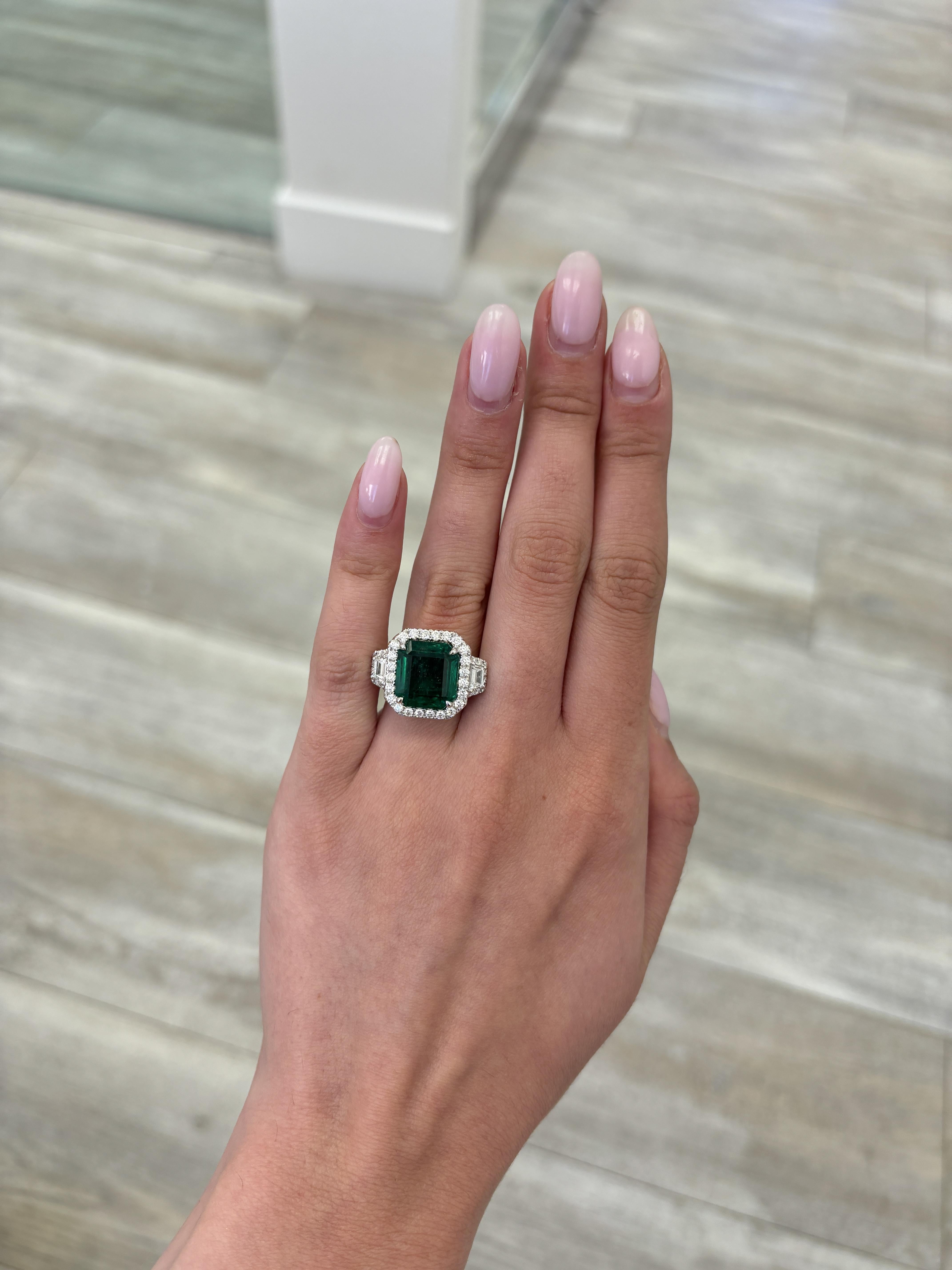 Stunning vivd green emerald of superb color with diamond three stone halo ring, GIA certified. High jewelry by Alexander Beverly Hills.
8.96 carats total gemstone weight.
7.57 carat square emerald cut emerald, GIA certified, moderate. 2 trapezoid