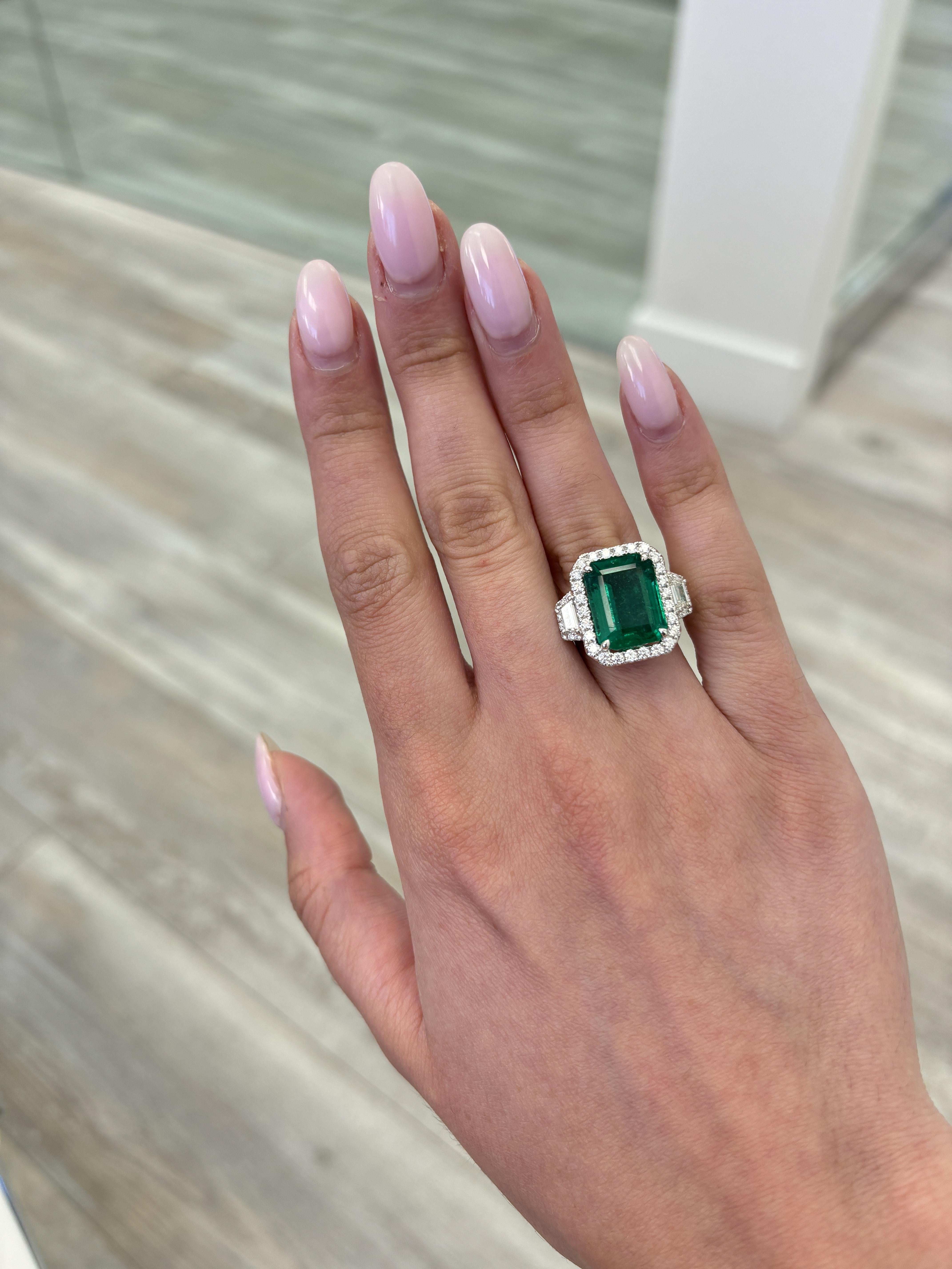 Stunning vivd green emerald of superb color with diamond three stone halo ring, GIA certified. High jewelry by Alexander Beverly Hills.
9.38 carats total gemstone weight.
8.99 carat emerald cut emerald, GIA certified, moderate. 2 trapezoid diamonds