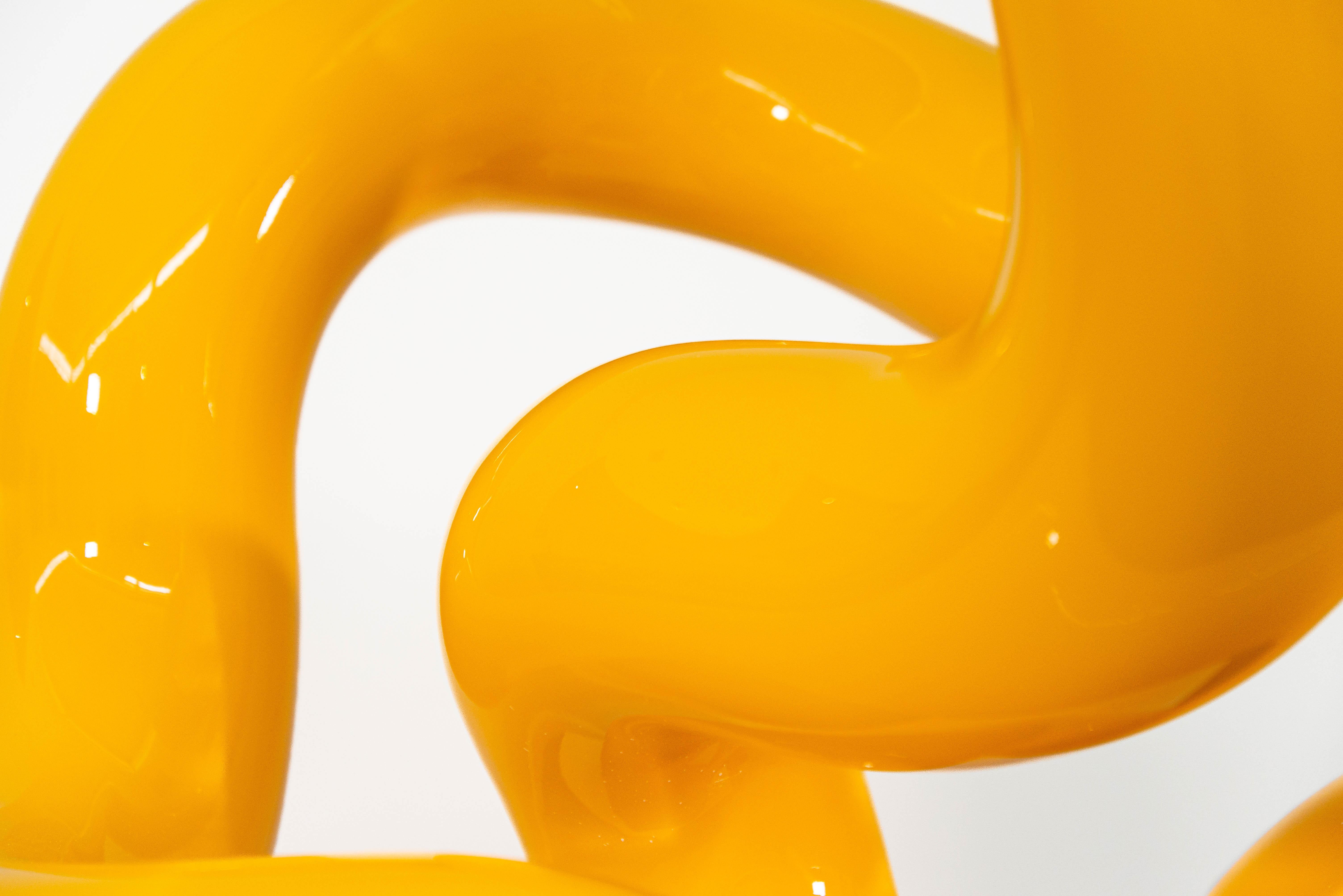 The shiny bright yellow colour of this engaging sculpture accentuates its elegant form.
This is Alexander Caldwell. The Calgary based artist is known for his playful, minimalist pieces forged from stainless steel and coated in a high gloss paint.