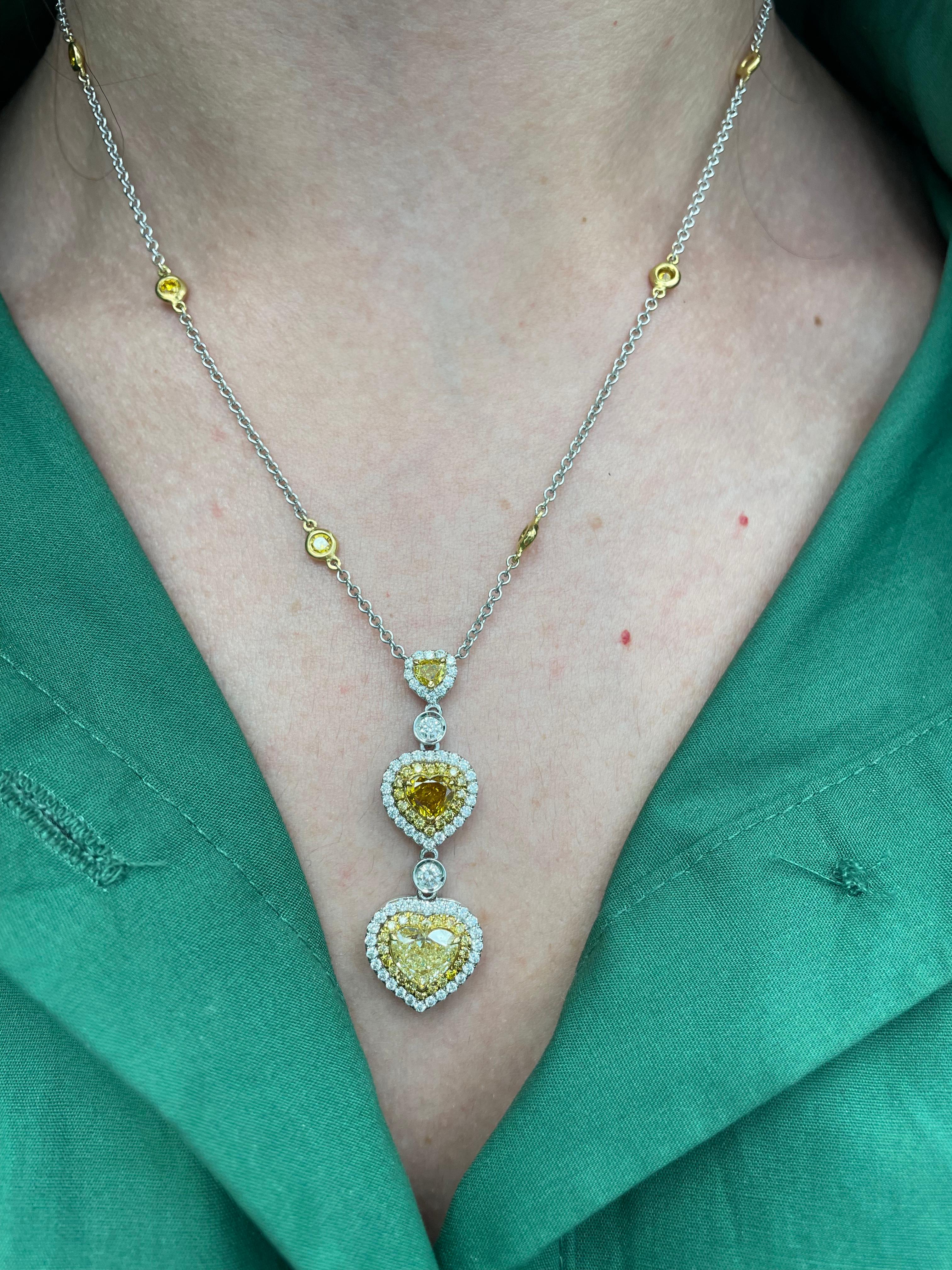 Exquisite heart shape fancy color diamond drop pendant necklace with double diamond halos GIA certified, by Alexander Beverly Hills.
3 heart shape diamonds ranging from Fancy Yellow to Fancy Deep Orange-Yellow color grade, 2.47ct. Complimented by