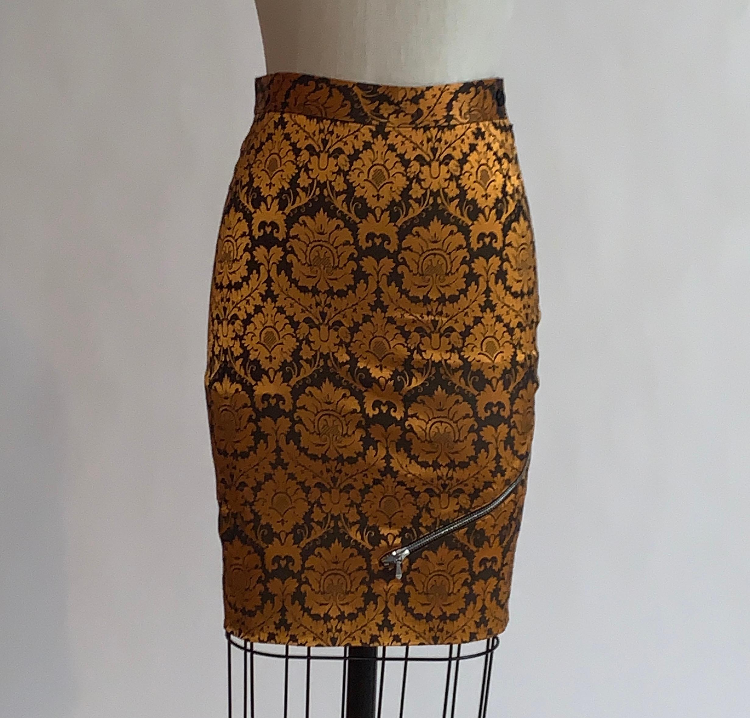 Alexander McQueen orange and brown brocade pencil skirt, midi version shown in look 18 of the Spring 1997 runway show La Poupee. Working zipper detail wraps from front to back. Side zip with button and snap at waist.

68% acetate, 20% cotton, 4%