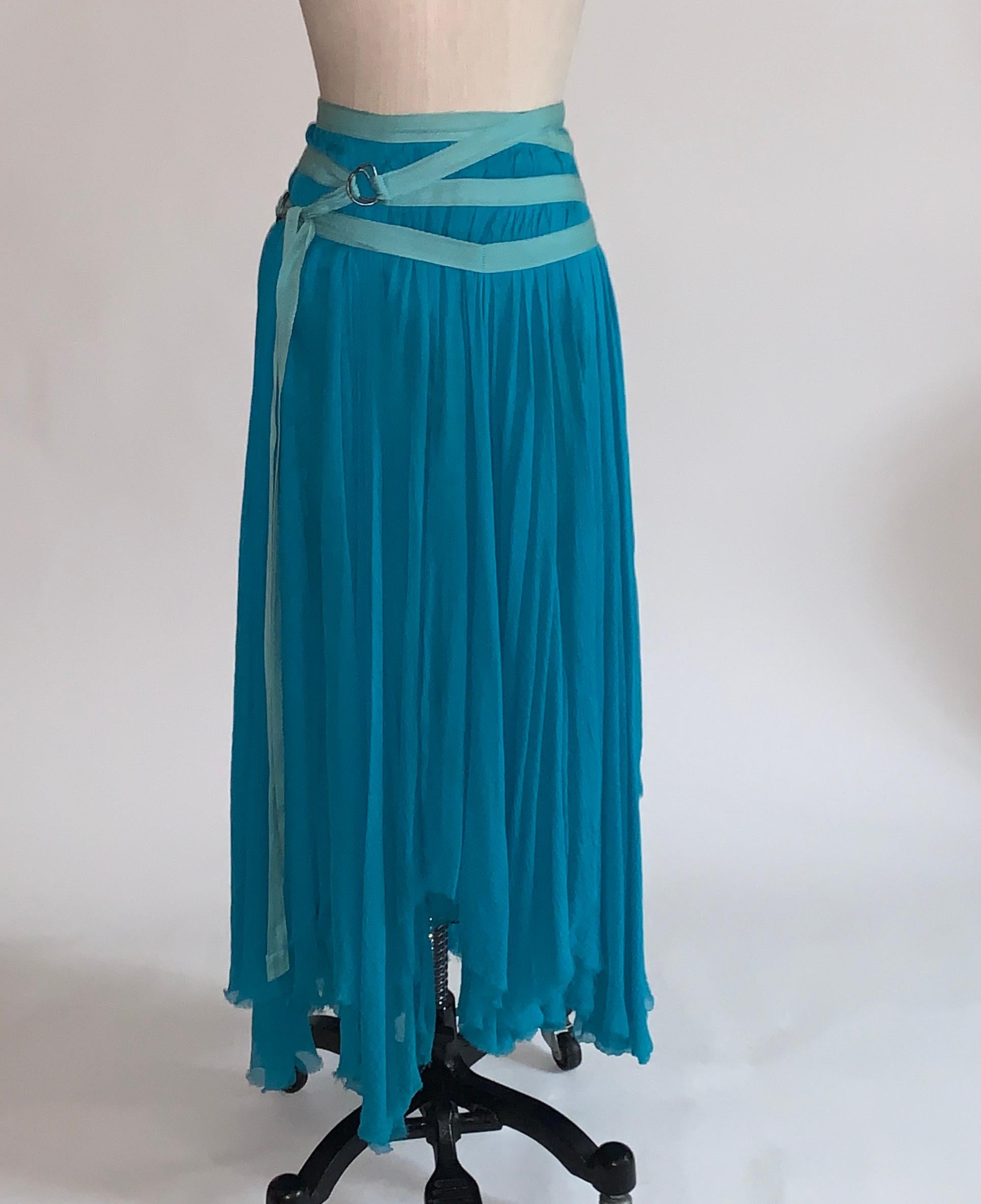 Alexander McQueen flowing blue skirt with criss cross straps at hip and asymmetrical (raw edged) distressed hem. Semi sheer, top 8 inches are lined. Sits low on the hip. Back zip and hook and eye.  Produced for the Spring 2003 Irere collection. 