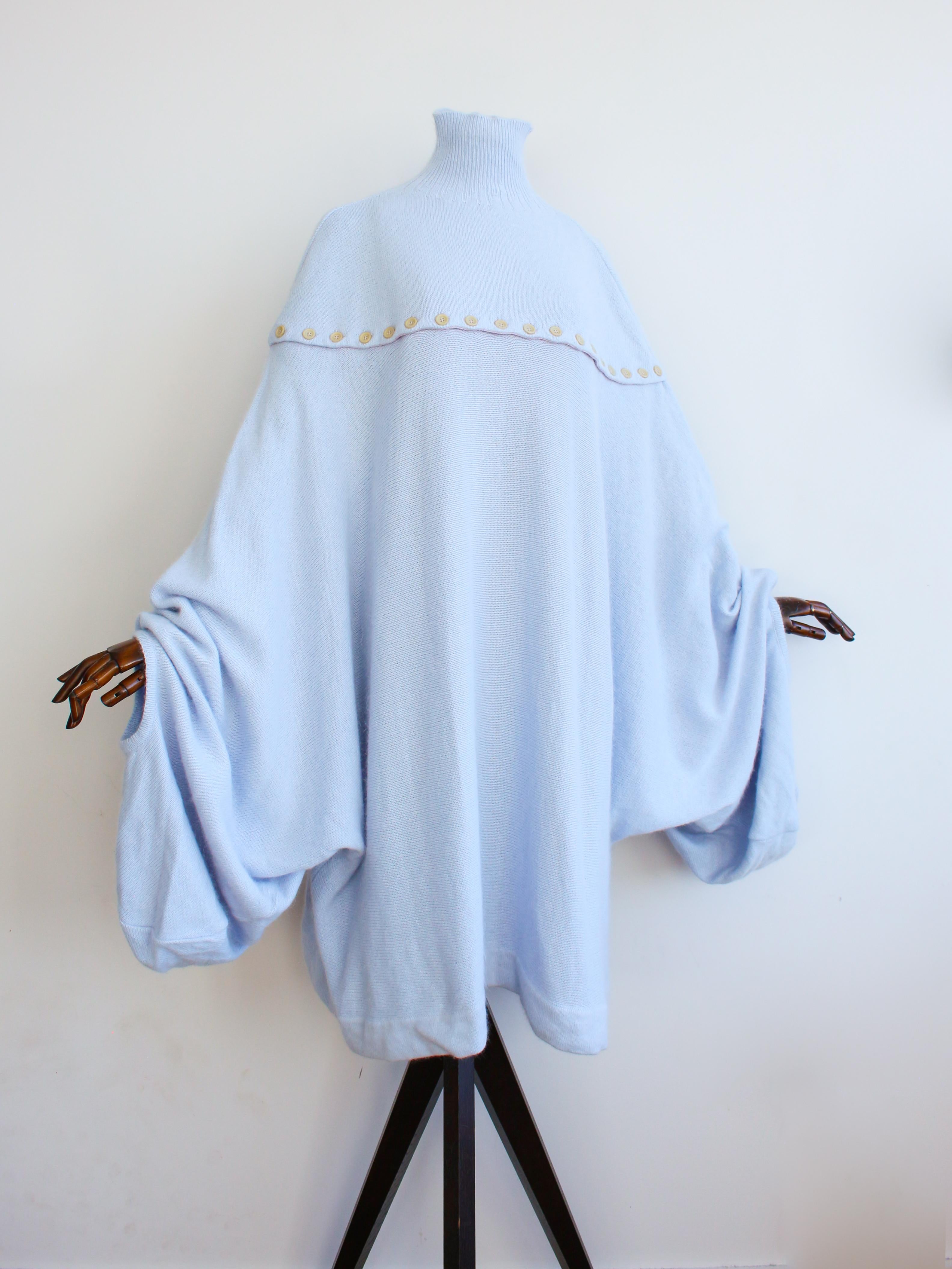 Jersey Alexander McQueen Otoño/Invierno 1996 'Dante' de punto azul hielo con mangas extremadamente sobredimensionadas.

Los botones funcionales rodean completamente el pecho, la pieza se mantiene unida en las costuras laterales, por lo que no se