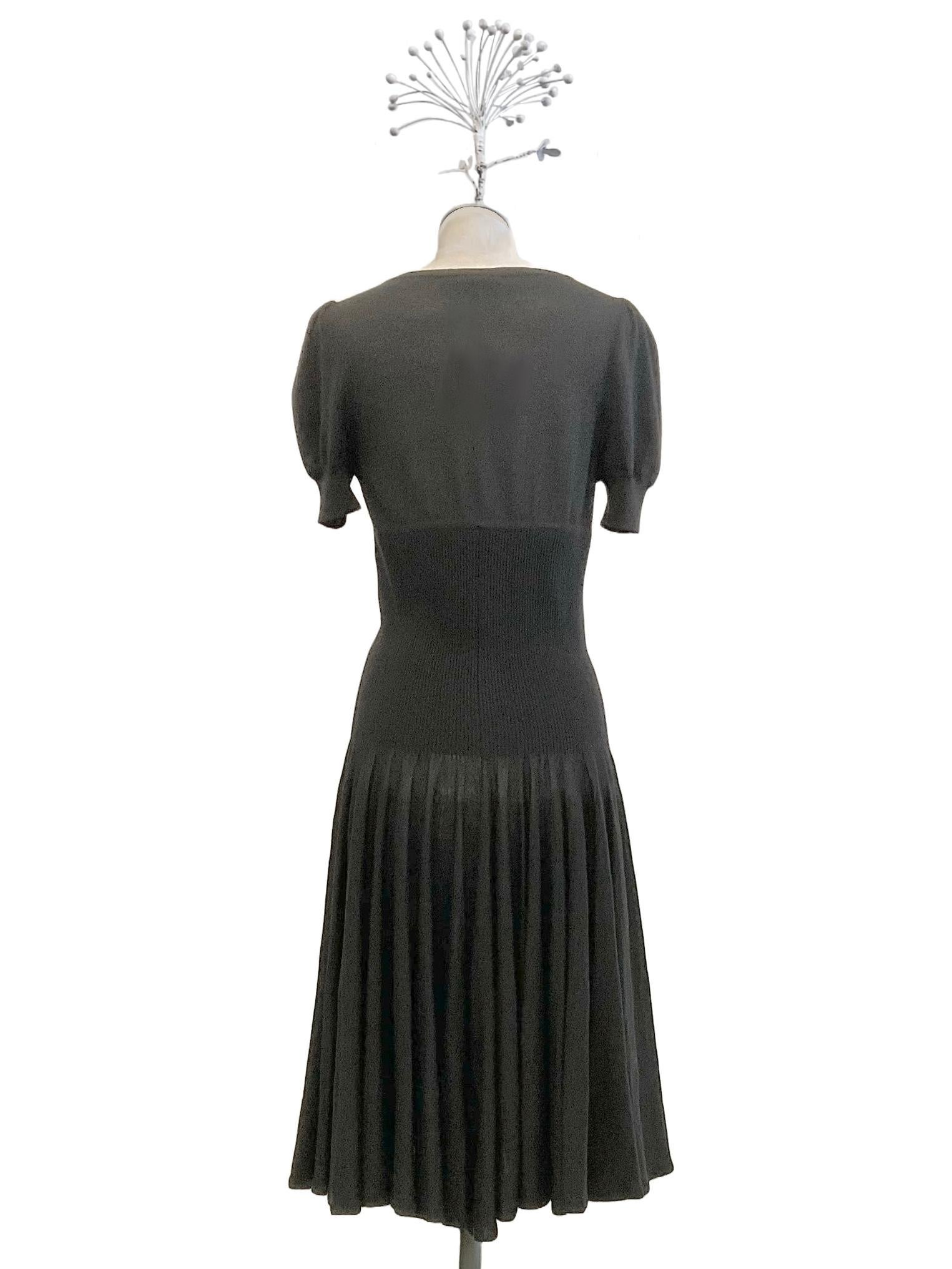 Alexander McQueen black midi dress with fitted waistline and
wide skirt flared toward the bottom.
The neckline is V-neck and the short sleeve is slightly puffed.
The silhouette is emphasized by dense fine ribbing.
The dress is made of fine knit with