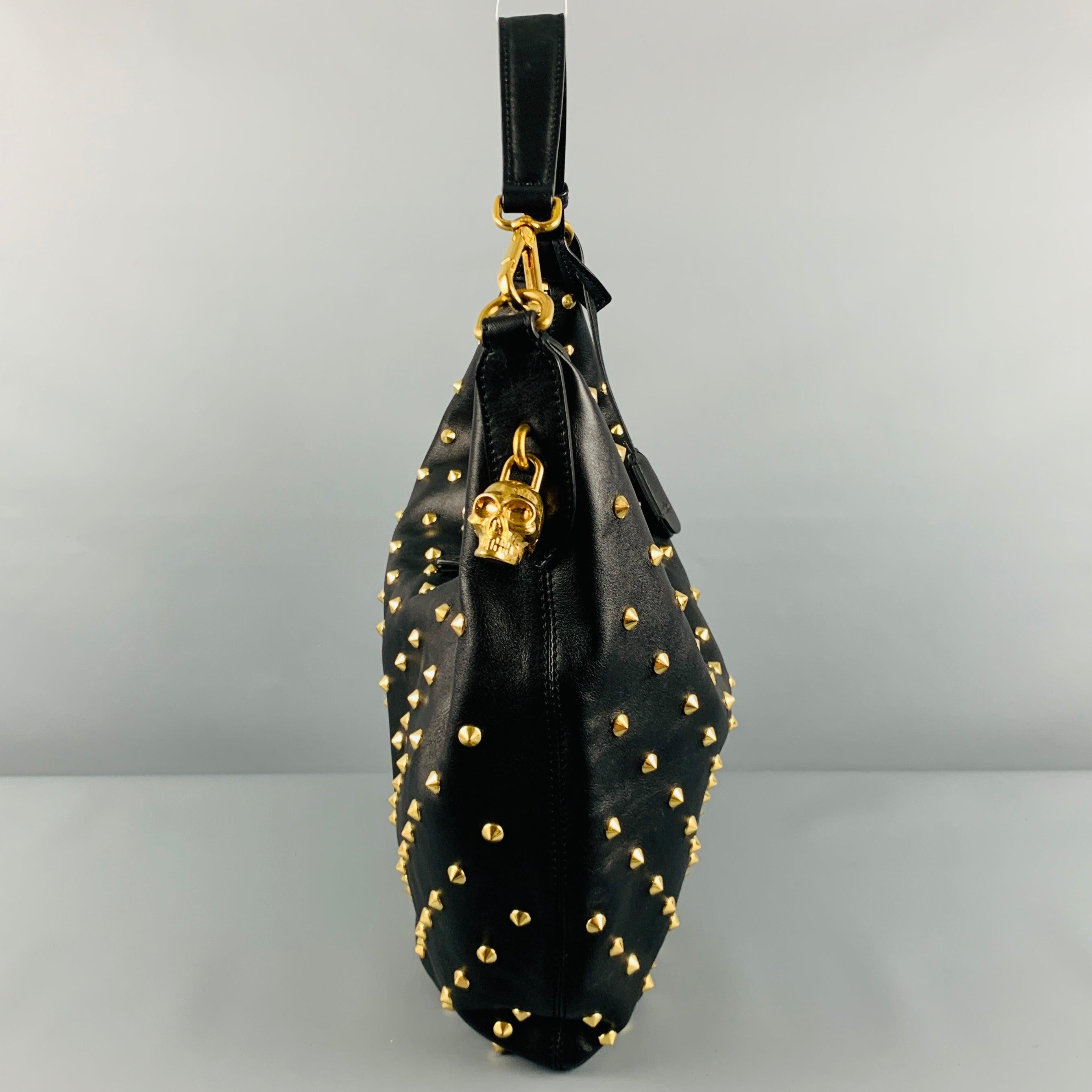 ALEXANDER MCQUEEN Handtasche
aus schwarzem Leder im Hobo-Stil, mit goldfarbenen Nieten und doppeltem Reißverschluss mit Totenkopf-Vorhängeschloss und Schlüsseln. Sehr guter, gebrauchter Zustand. 

Abmessungen: 
  Länge: 17,5 Zoll Breite: 1,5 Zoll