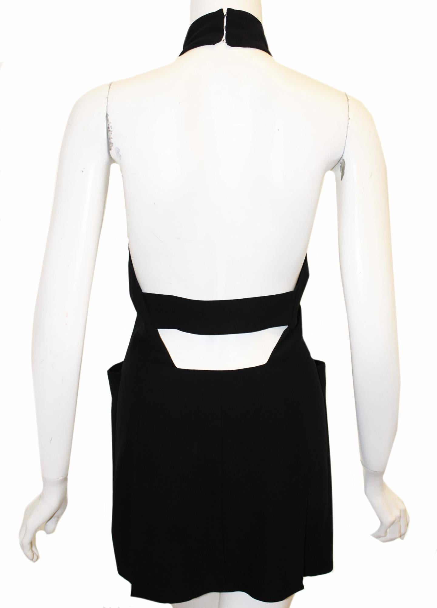 Alexander McQueen black halter mini dress incorporates a plunging V neck at front decorated with covered buckle.   Two large bucket pockets at each side of dress.  The halter top wraps around the neck and closes with 2 large hook and eye, at back. 