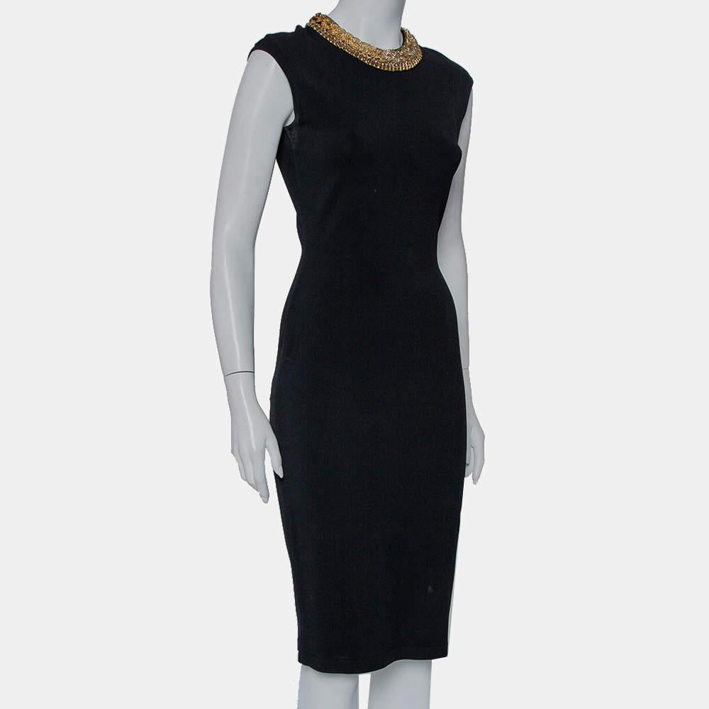 A sleeveless sheath dress with an embellished neckline makes up the final design of this Balenciaga creation. Beautiful in black, the dress has a defined shape, knee-length hemline, and button closure.

