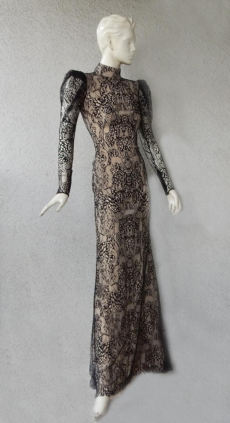 Alexander McQueen form fitting evening gown fashioned of black lace emphasizing  a striking but simple elegant silhouette.   Designed in an intricate butterfly lace pattern with mock neckline and 3 button back closures.  Long slender zipper sleeves