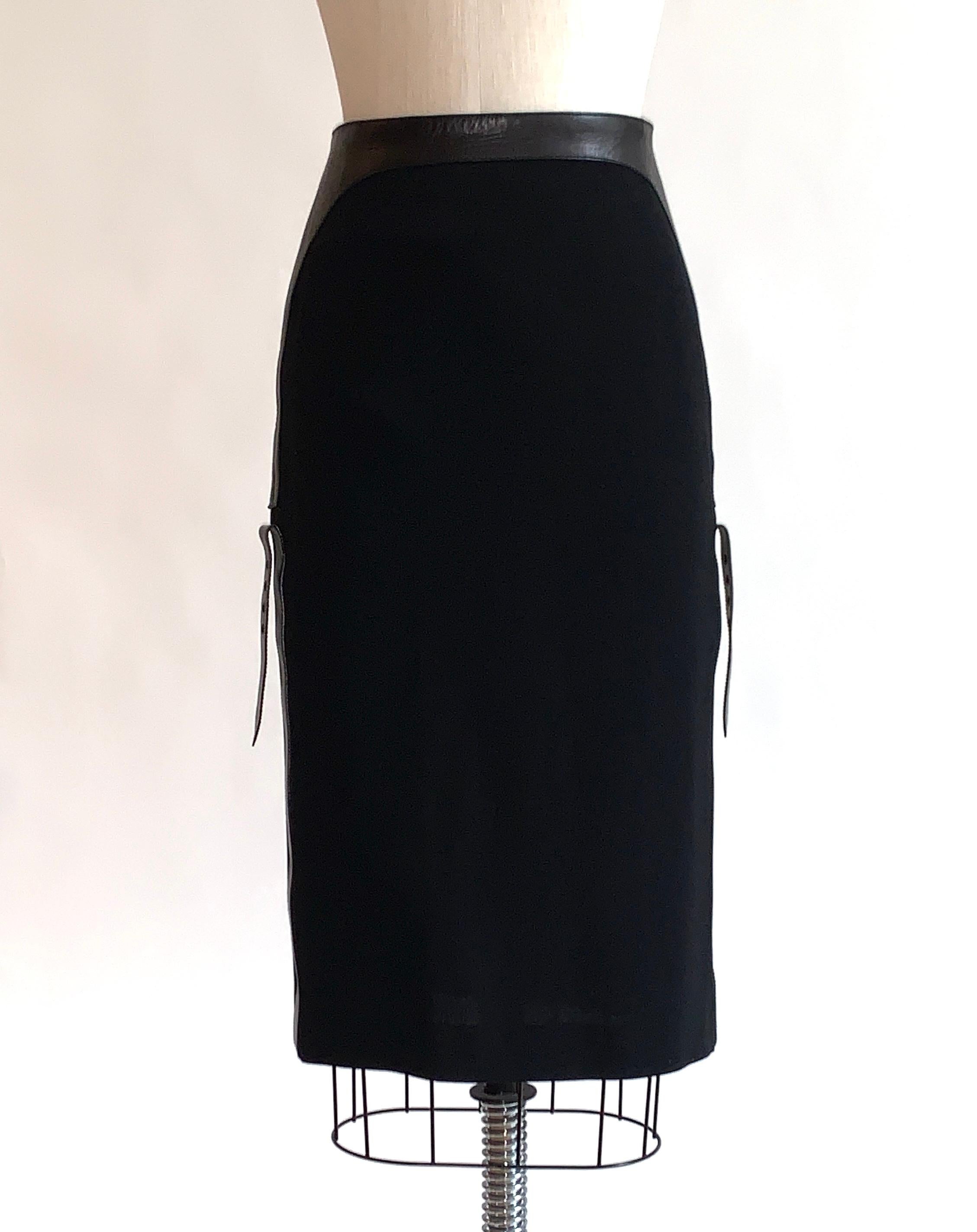 Alexander McQueen black pencil skirt with leather accent at waist that descends into straps at side.  Zip at back waist, slit at back center.

90% wool, 10% leather.
Fully lined in 100% rayon.

Made in Italy.

Size Italian 40, approximate US 4. See