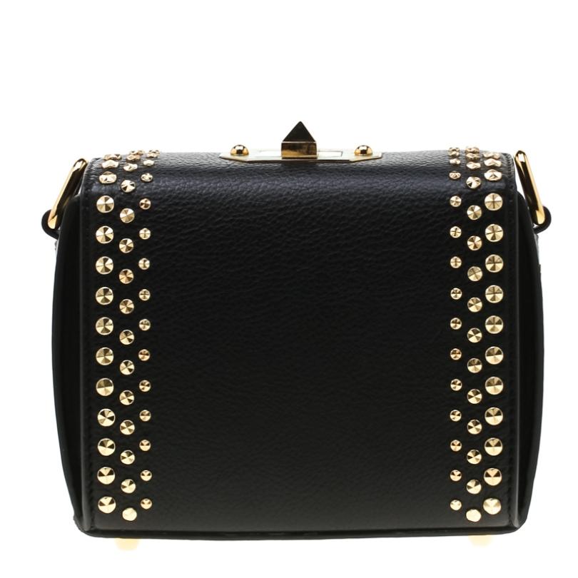 This Alexander McQueen Studded Box bag is sure to make you stand out and grab all the compliments! It is crafted from leather and features a boxy silhouette. It flaunts the brand name on the front along with gold-tone stud embellishments. It has a