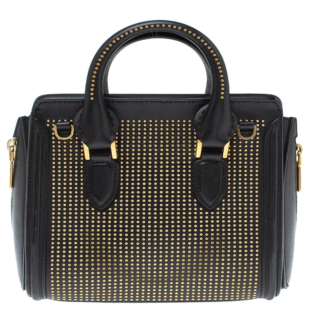 Great space and detailed design are found in this Heroine bag by Alexander McQueen. Crafted from leather, the bag has an allover studded design in gold-tone hardware, has five metal feet and this satchel has dual leather top handles and a zip