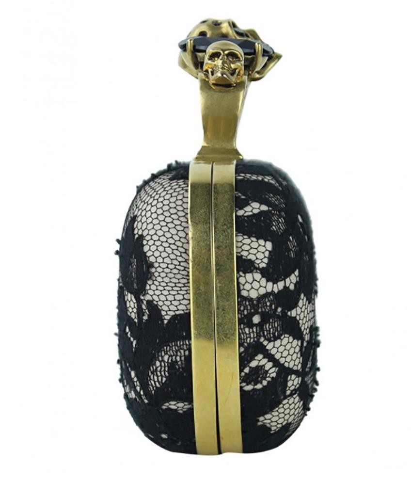 ALEXANDER MCQUEEN
	
Alexander McQueen Knuckle Duster Lace Original Clutch in raso champagne con sovrapposizione di pizzo nero. Presenta un design rettangolare strutturato, finiture dorate, un unico scomparto e un unico cinturino a mano con