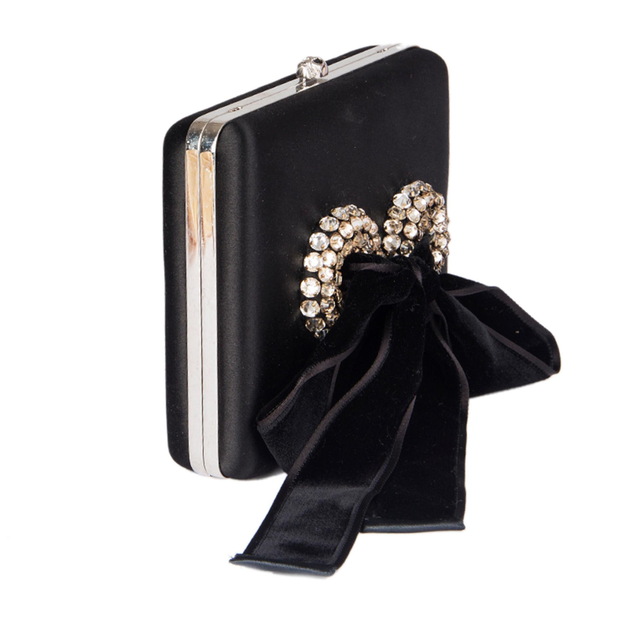 100% authentic Alexander McQueen box clutch in black satin with velvet and rhinestone ribbon on the front. Detachable chain strap in silver-tone metal. Opens with a small skull push-lock. Lined in black leather with an open pocket against the back.