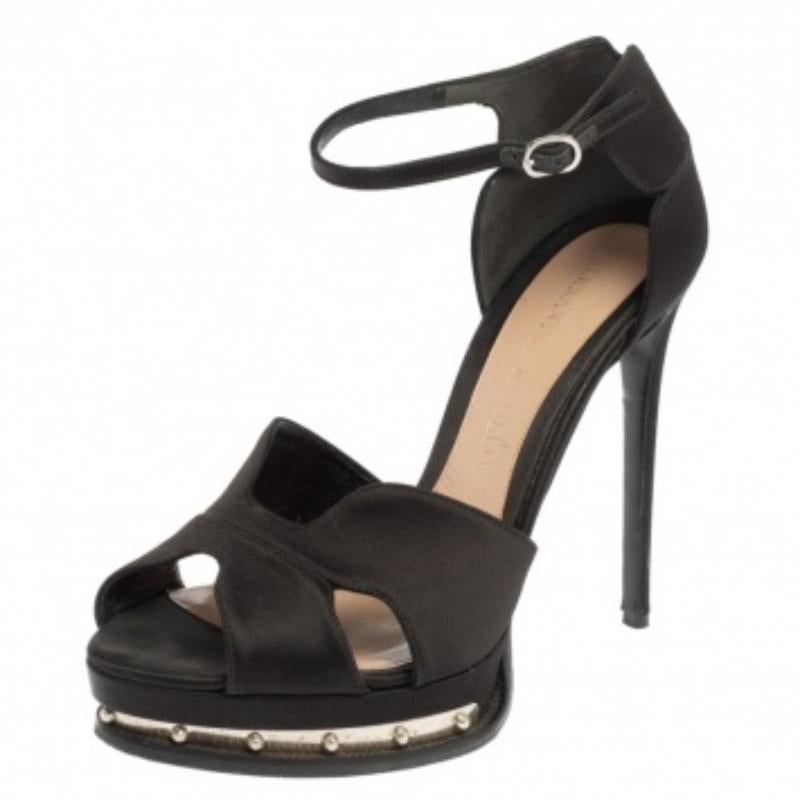 Faites chaque pas avec élégance et style grâce à ces sandales signées Alexander McQueen. Elles sont confectionnées avec soin en satin noir et ornées de clous sur les semelles compensées. Ils sont dotés d'une bride à la cheville, d'accessoires en