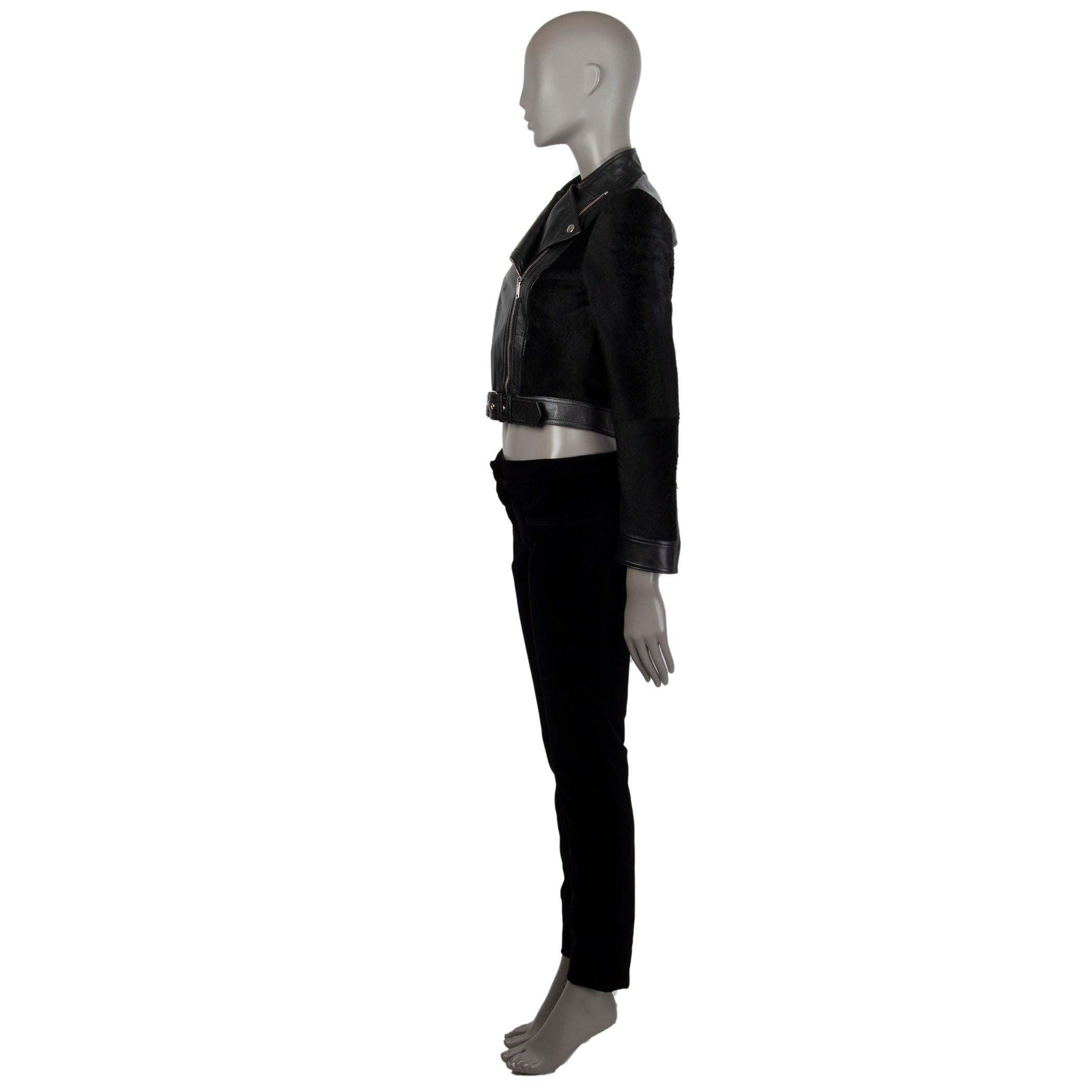 Alexander McQueen biker jacket in black shearling and leather with a frontal asymmetrical zipper pocket. Has a band collar that can be worn open with snap buttons. Closes on the front with a silver tone zipper and buckles with an attached belt on