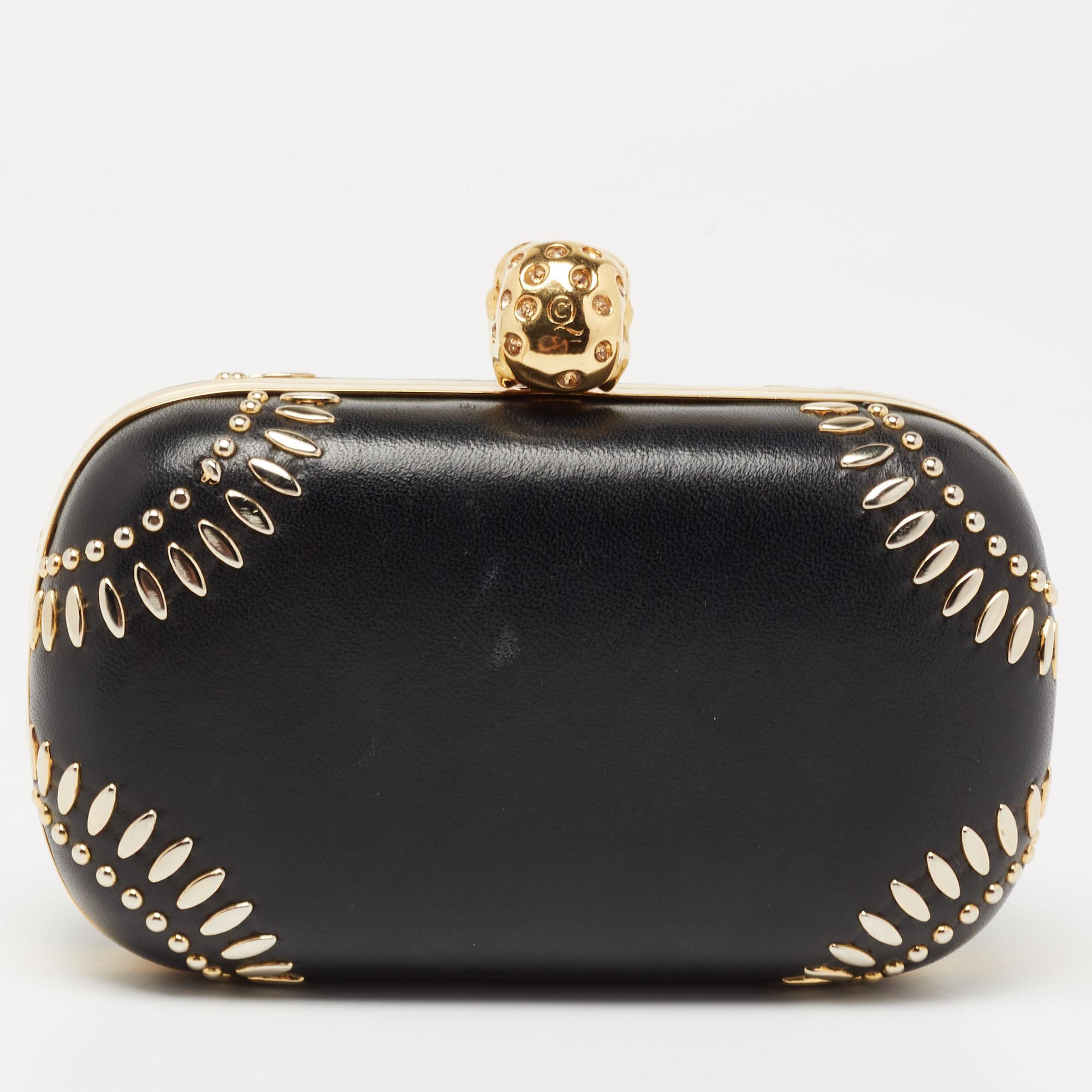 This small clutch from Alexander McQueen exudes a luxurious style. Crafted from black leather and gold-tone metal, it has a sleek finish and comes with a lined interior. This piece is complete with an embellished skull accent on top. Flaunt this