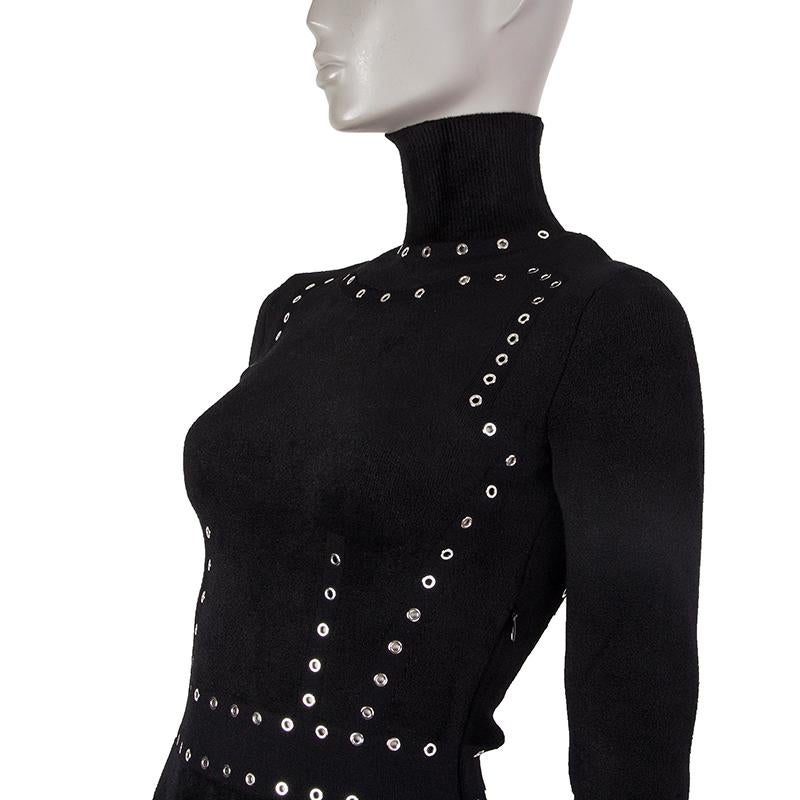 Alexander McQueen long-sleeve knit dress in black viscose (67%), nylon (24%), polyester (7%), and elastane (2%). With turleneck, eyelet studs, and flared hemline. Closes with invisible zipper on the side. Unlined. Has been worn and is in excellent