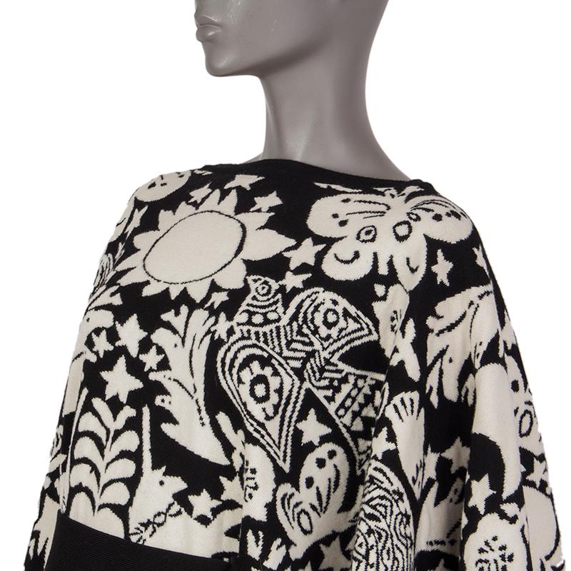 Alexander McQueen 'Naive Pagan' jacquard-knit cape in black and off-white wool blend (assumed as tag is missing). With two belt loops on the front. Unlined. Comes with belt strap in black knit. Has been worn and is in excellent condition. 

Tag Size
