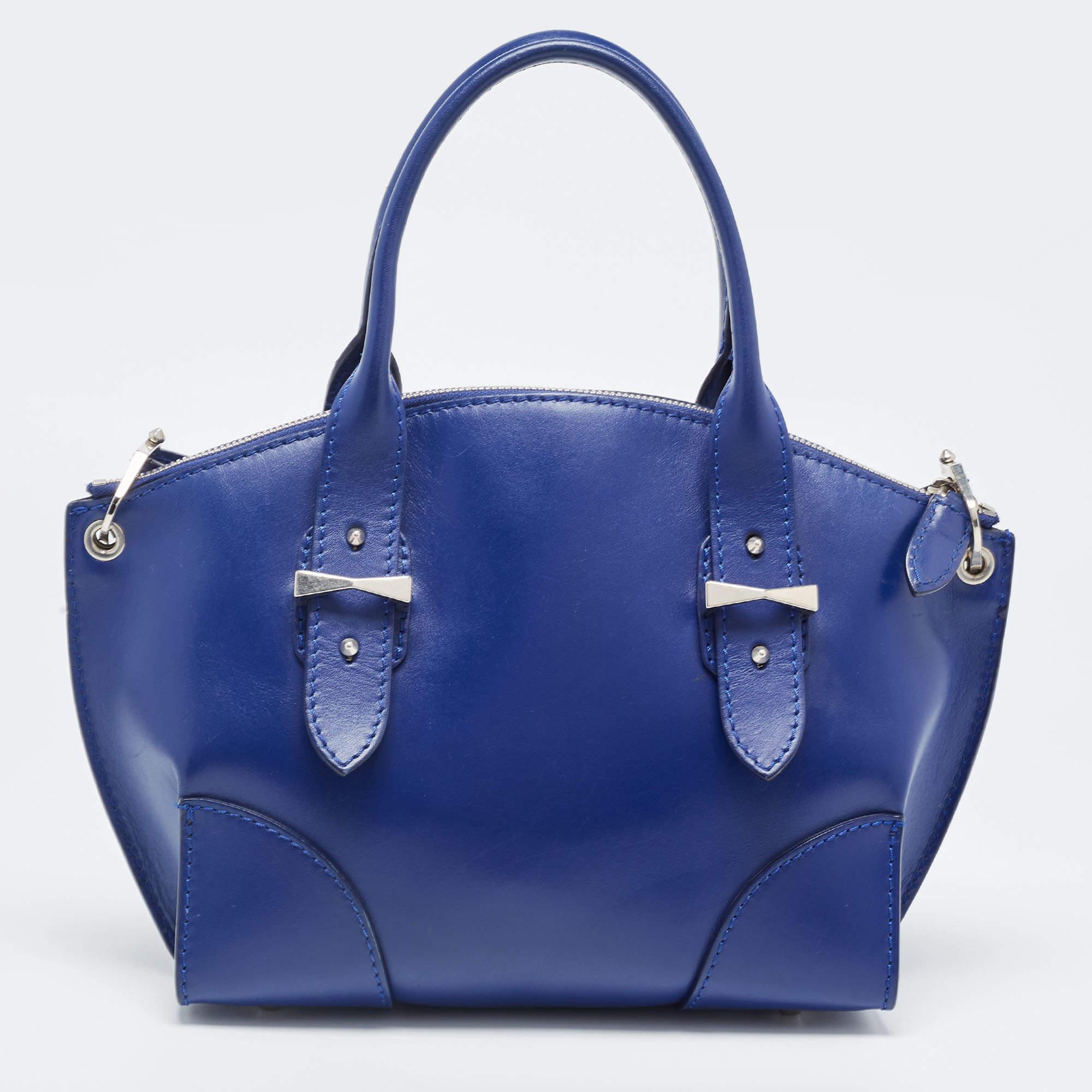 Add a dash of color to your outfit with this blue Legend tote from Alexander McQueen. Crafted from leather, it features a structured body, top round handles supported with silver-tone buckles, and a removable leather strap. The bag is secured with a