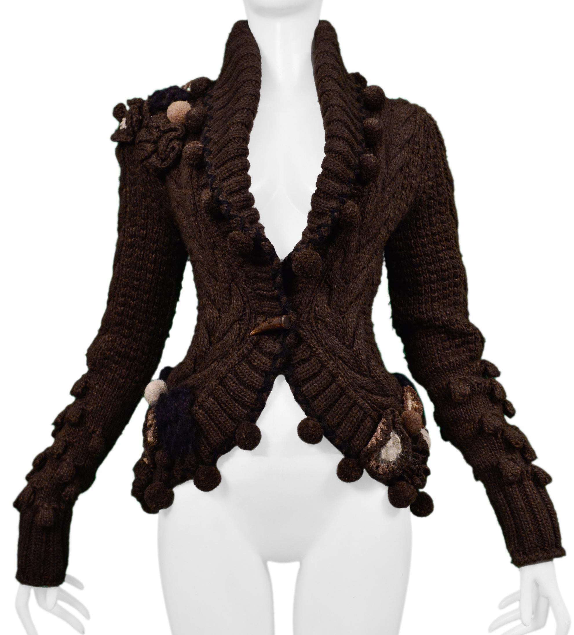 Resurrection is excited to offer a vintage Alexander McQueen brown fancy cardigan sweater featuring detailed floral applique, pom-poms, horn button, high neck, and a fitted body. 

Alexander McQueen 
Size Small
Lana Wool
2005 Collection 
Excellent