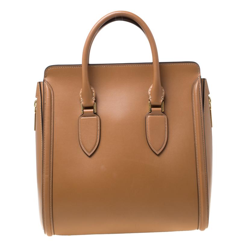 Handbags are more than just instruments to carry one's essentials. They tell a woman's sense of style. Alexander McQueen brings you one such bag meticulously made from leather. This Heroine satchel has a suede interior secured by a flap and it is
