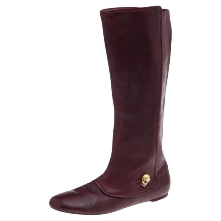 Creations as fashionable as this pair of knee-length boots from Alexander McQueen deserve to be in every woman's closet. They've been created from brown leather and designed with round toes, signature skull charms, and tough soles.
