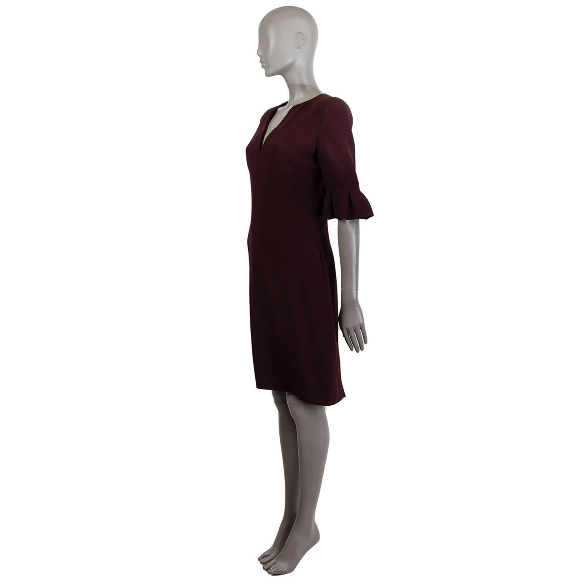 Alexander McQueen short-sleeve knee-length sheath v-neck dress in burgundy acetate (50%) and rayon (50%). Lined in acetate (74%) and silk (26%). Dress features padded shoulders and pleaded detail at sleeve. Opens with a zipper on the back. Has been