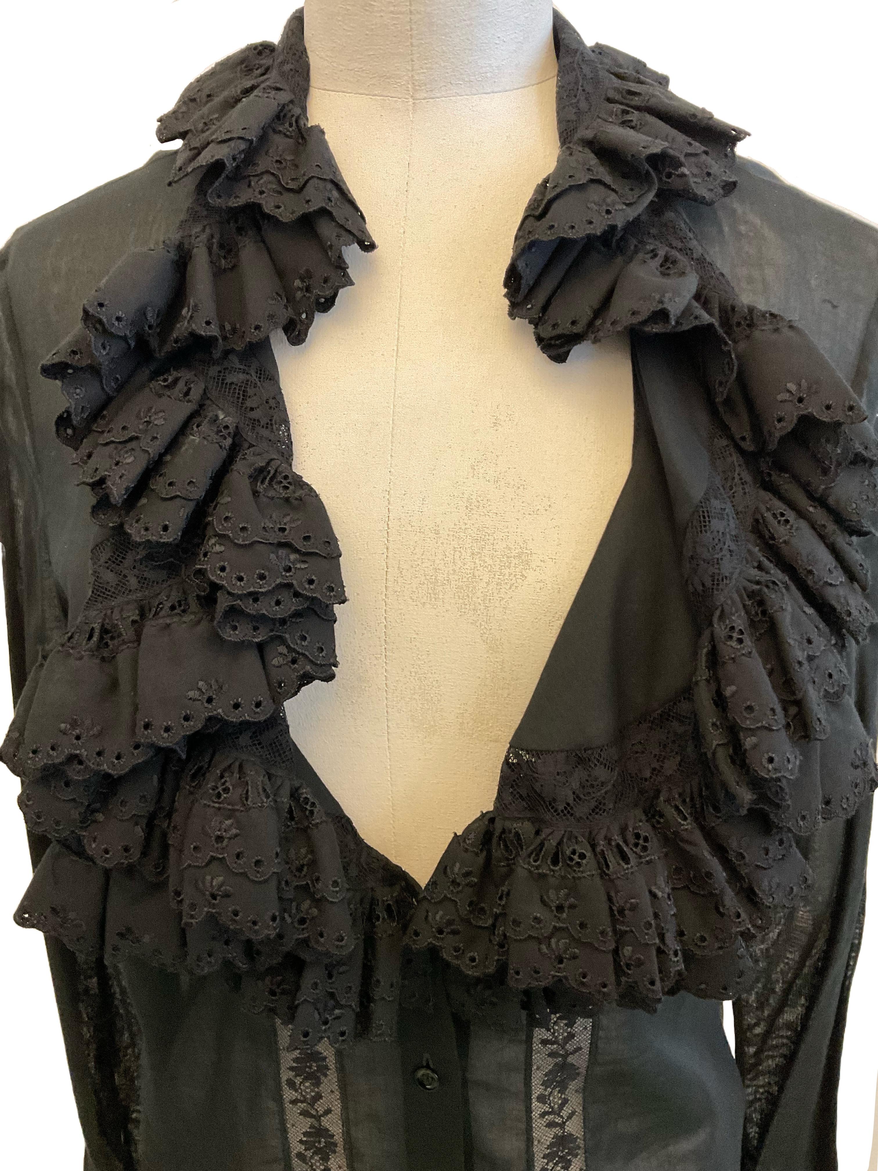 Chemise noire Alexander McQueen de la collection Prêt-à-porter
Portez l'automne-hiver 2006.
L'encolure est en V. Le biais de l'encolure est incrusté d'un ruban de dentelle et d'une bande de tissu
se termine par une double rangée de volants brodés de