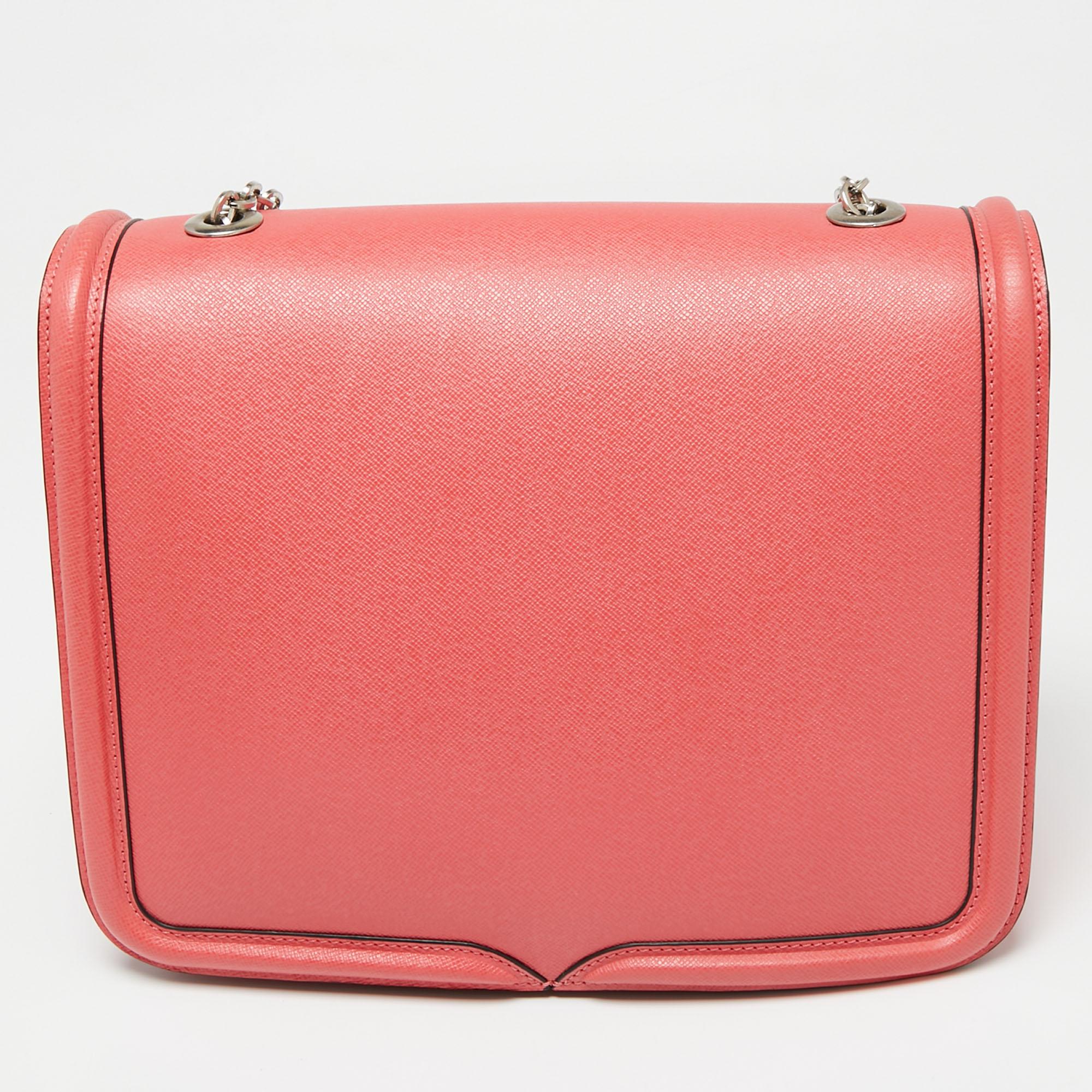 The uniquely designed front flap of this Alexander McQueen bag adds to its overall appearance. Crafted from leather, it is defined by a chain-leather shoulder strap, a suede-lined interior, and gold-tone hardware. The coral pink shade of this bag