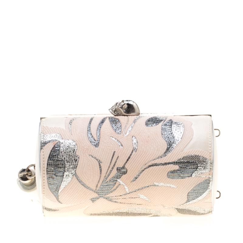 This clutch by Alexander McQueen is one you will love carrying around. It is subtle, captivating, and stylish. The clutch is made from cream satin and covered in soothing florals. The signature skull on top opens to a leather interior and to