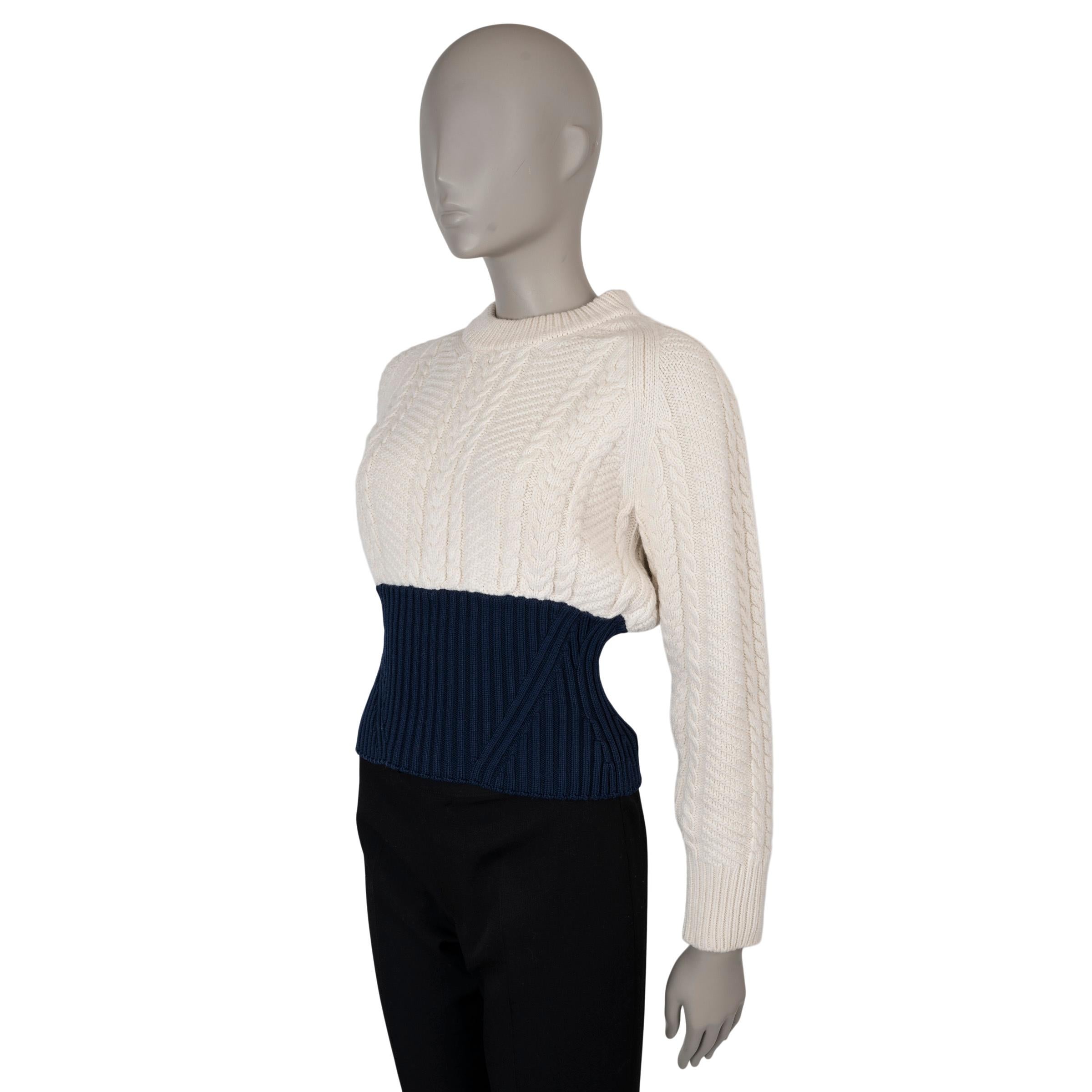 This 100% authentic Alexander McQueen colorblock sweater is crafted from a luxurious blend of cream cable-knit wool (90%) and cashmere (10%), accented with a navy blue rib-knit bottom for a bold contrast. It features a classic crewneck, raglan