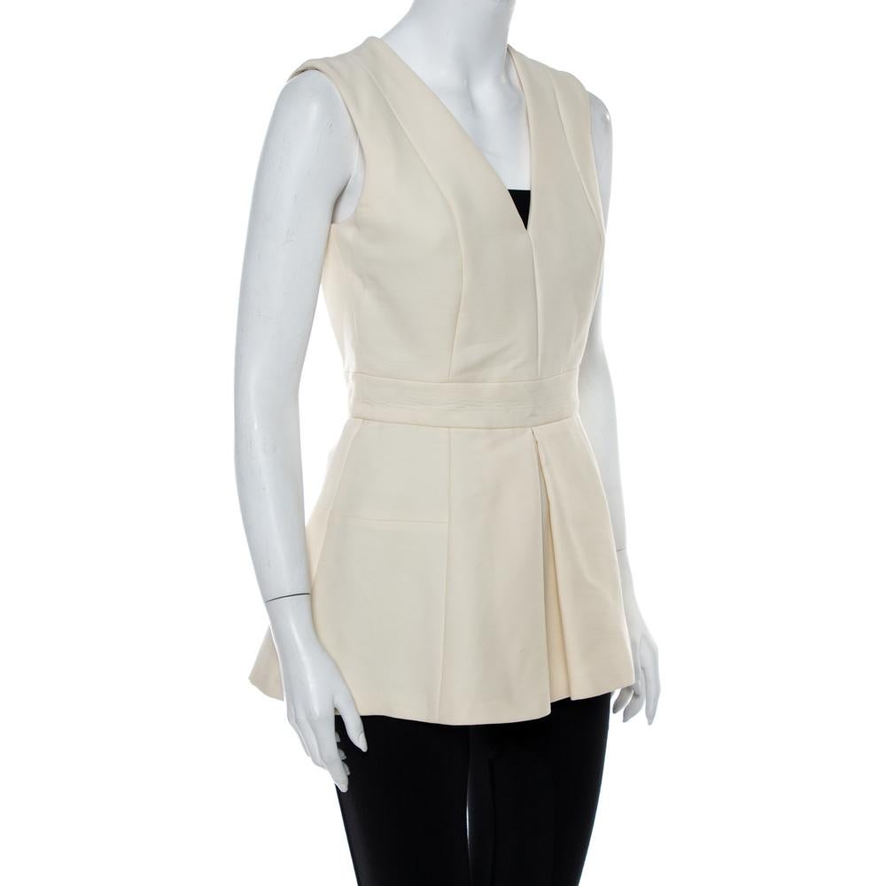 Alexander McQueen's Spring Summer 2016 collection exhibited smart tailoring along with delicate designs. This sleeveless top, made of cream-colored fabric, features a flattering peplum silhouette with a paneled design. Completed with a v-neckline,