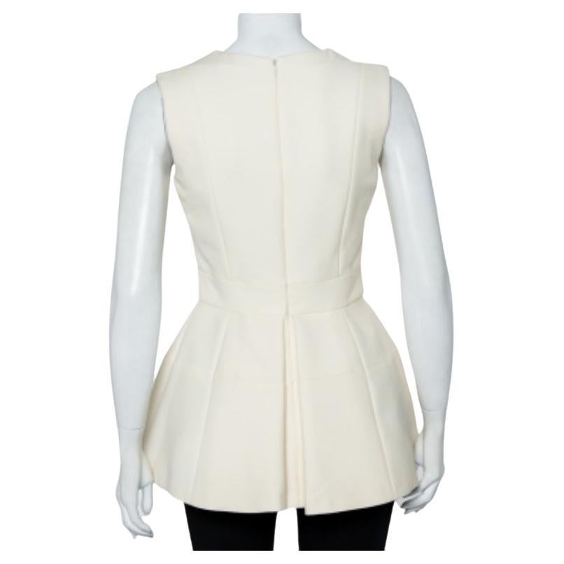 This top from Alexander McQueen exhibits smart tailoring and a delicate design. This sleeveless top, made of cream-colored fabric, features a flattering peplum silhouette. Completed with a v-neckline, wear this with cropped, fitted pants and