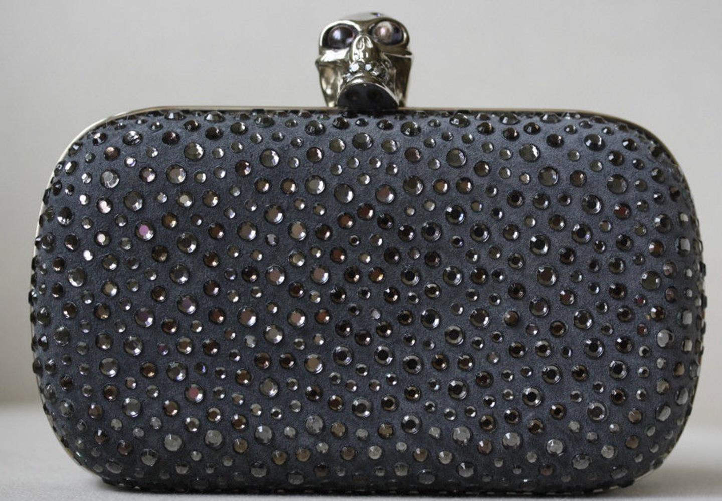 Get a rocker chic look with this edgy Alexander McQueen black crystal skull clutch. It will definitely style up any evening outfit. It features gorgeous grey crystal embellishments all over the exterior of the clutch, and a silver-tone skull on top