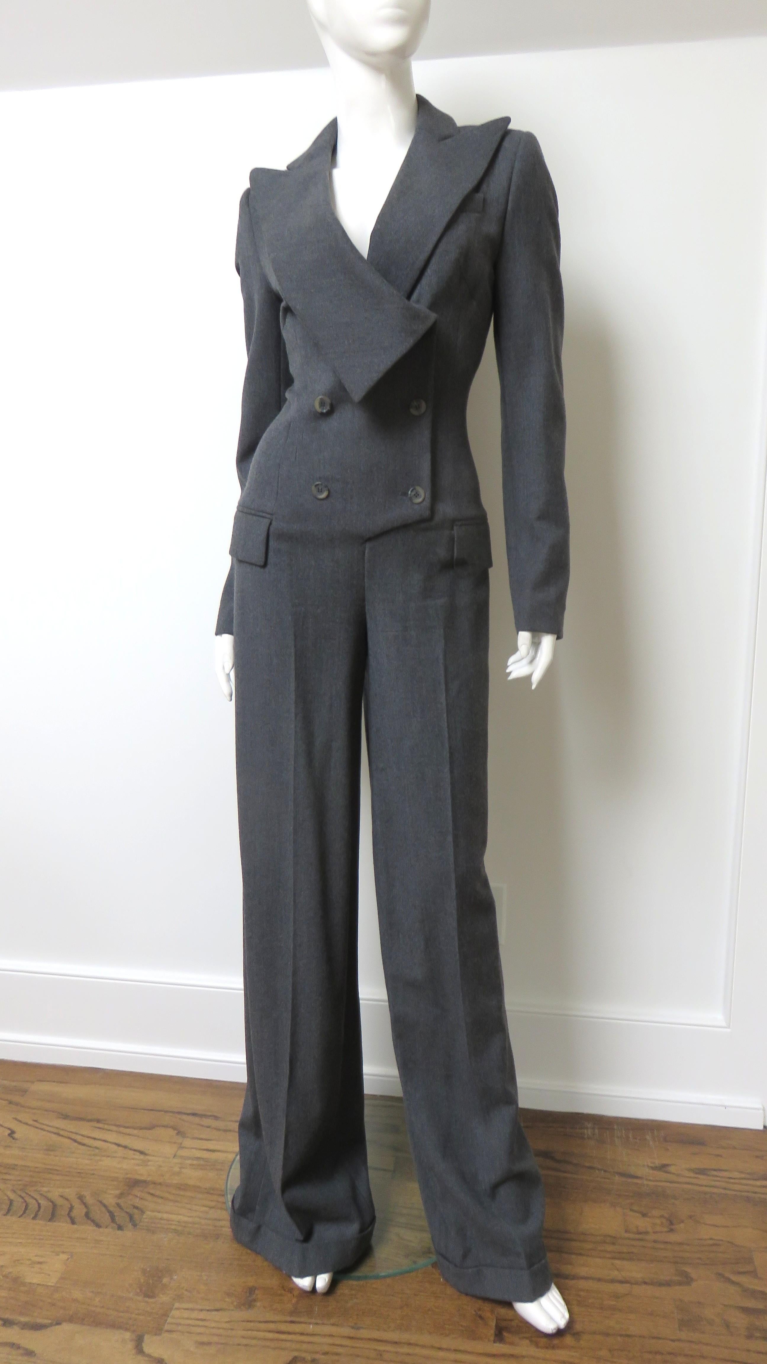 A stunning grey wool jumpsuit with a small amount of stretch for comfort by Alexander McQueen. It has a fitted double breasted drop waist torso with peak lapels, shoulder pads, hip welt flap pockets and clever inset side panels for enhanced fit. The