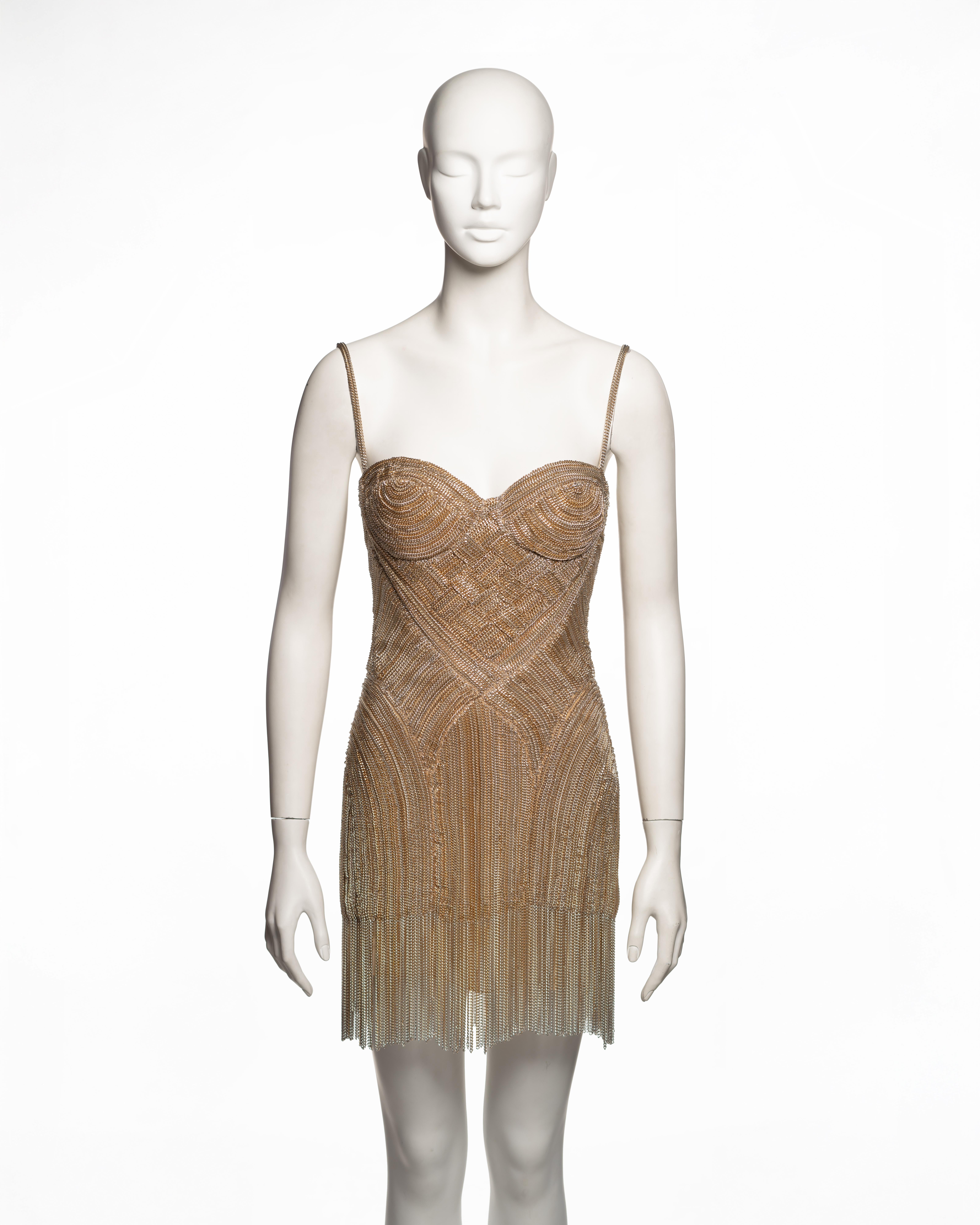 Mini abito di Alexander McQueen della collezione primavera-estate 2006, realizzato con catene in metallo dorato meticolosamente applicate su una struttura di base a rete. La silhouette aderente presenta un corpetto bustier sagomato con ricami a