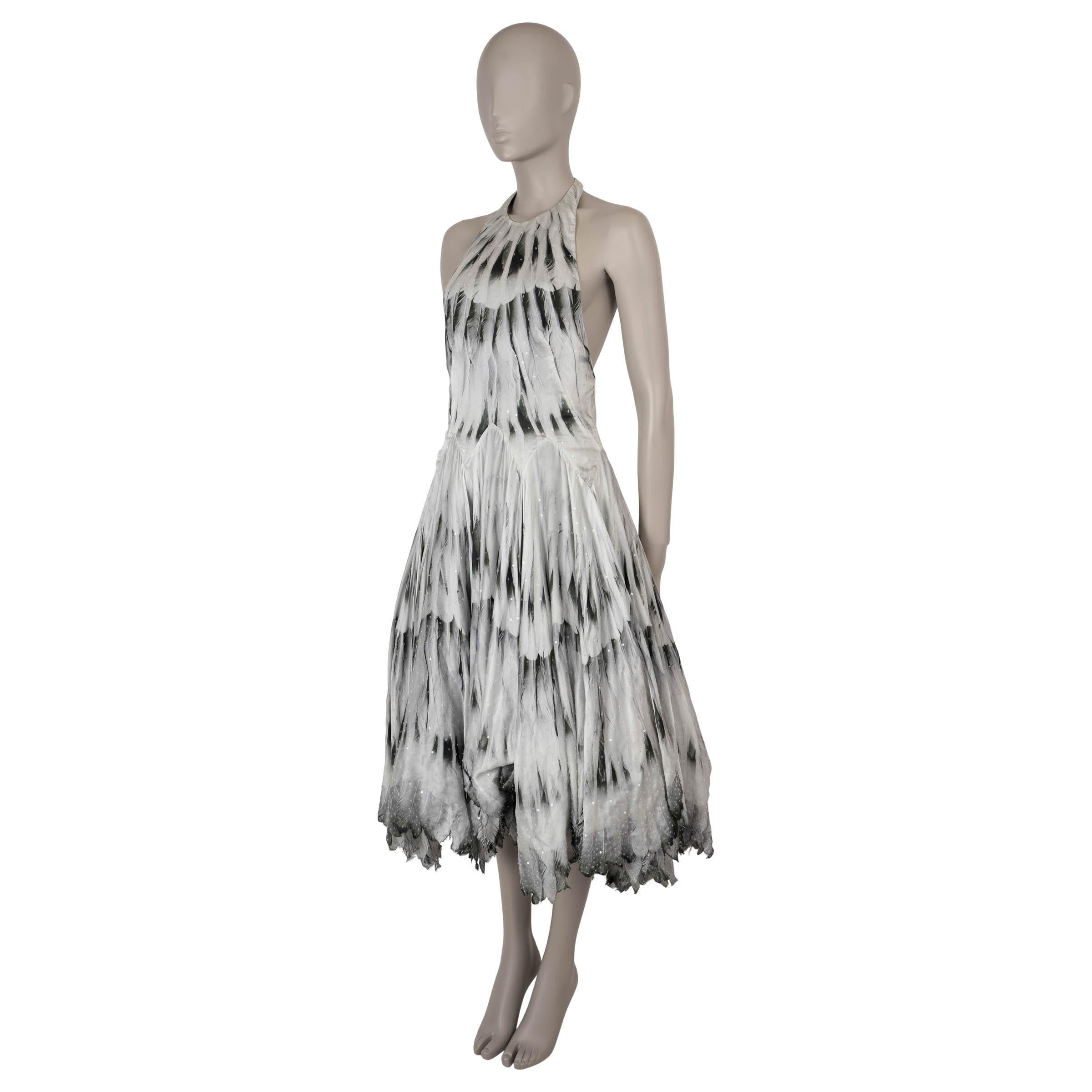 This 100% authentic Alexander McQueen cocktail dress in silver grey silk features a striking black and forest green feather print with clear sequin embellishments throughout, adding a touch of sparkle. The dress boasts a fitted halter top and a
