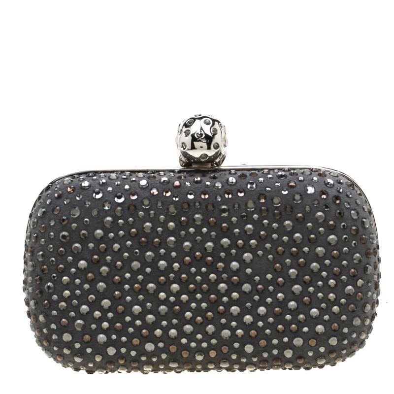 How utterly breathtaking is this clutch by Alexander McQueen! It is luxurious, well-crafted and overflowing with style. It has a grey nubuck leather exterior with gorgeous crystal embellishments and a skull lock on top. This creation will lift all