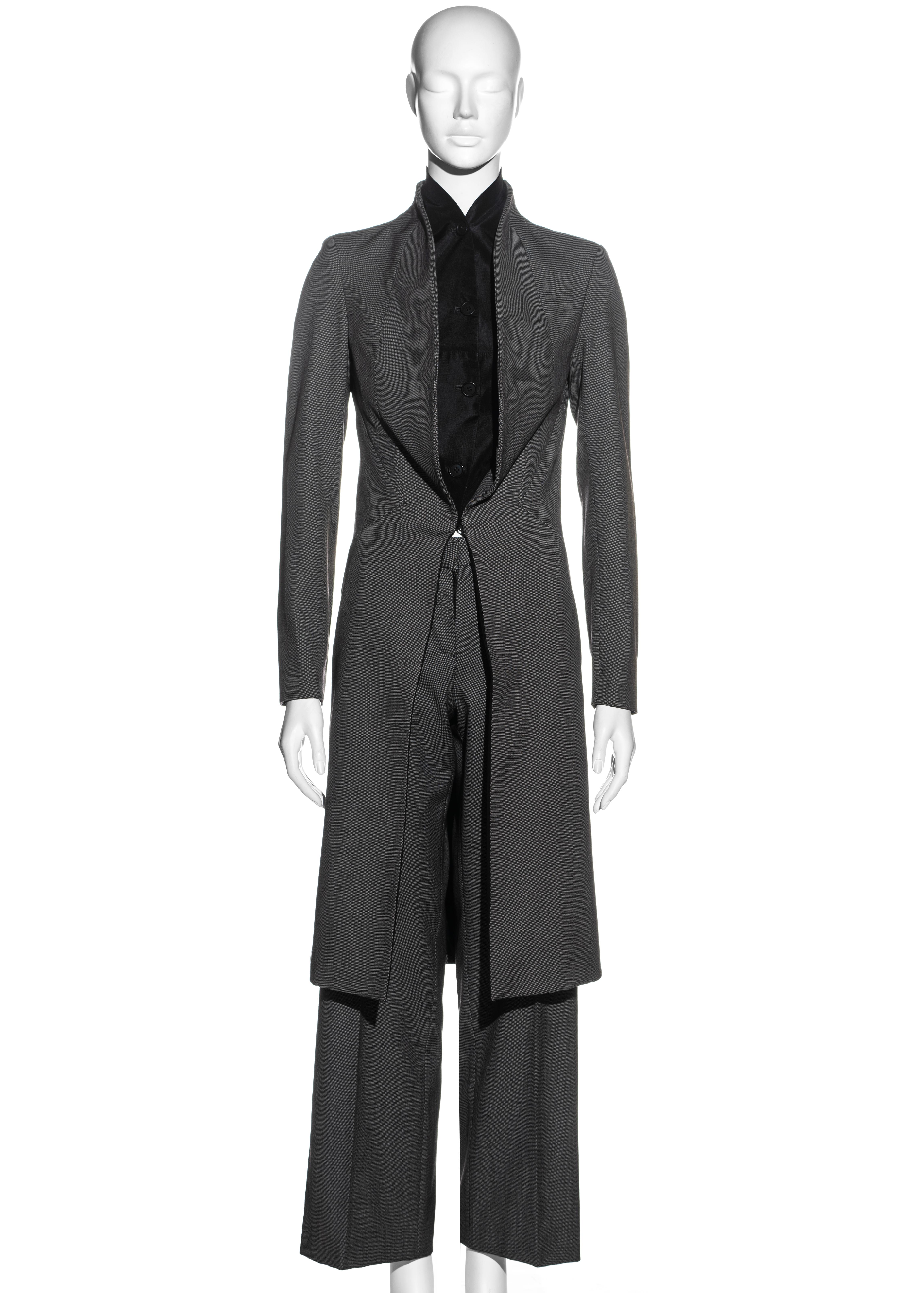 ▪ Alexander McQueen grey structured pant suit 
▪ Outer: 100% Wool, Lining: 100% Silk 
▪ Mid-length fitted jacket 
▪ Diamond cut panels to bodice 
▪ Standing shawl lapel 
▪ Metal hook closure at waist 
▪ Built-in black silk button-up panel at bust 
▪